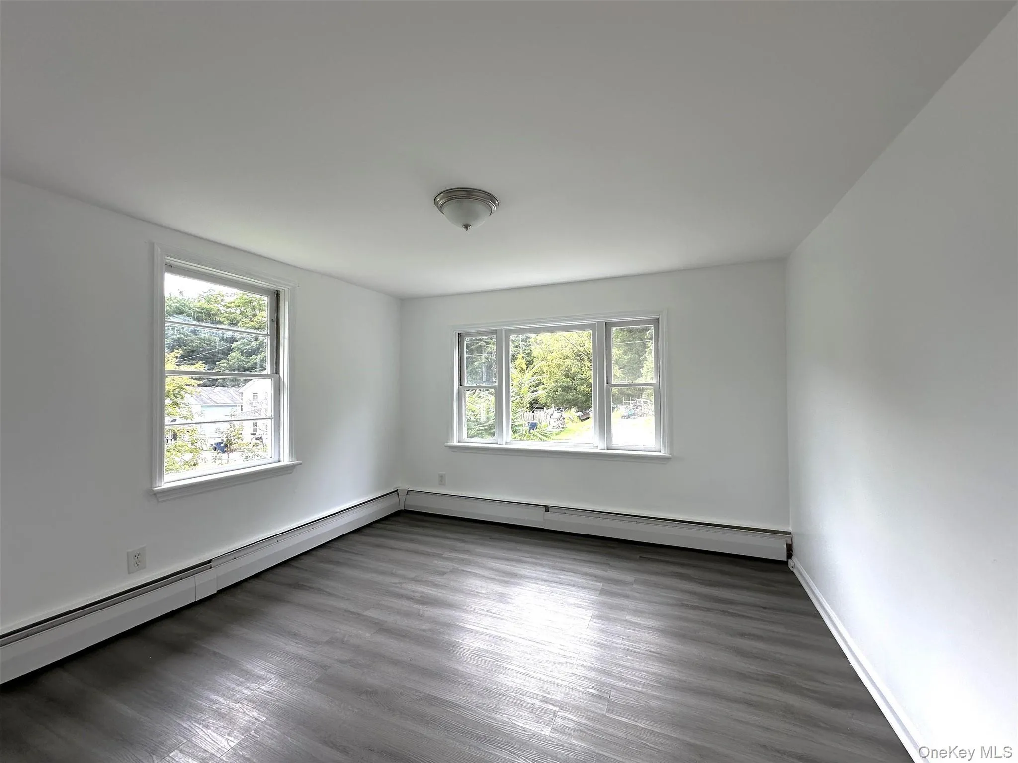Spare room with dark wood-style flooring and a baseboard heating unit Spare room with dark wood-style flooring and a baseboard heating unit