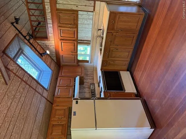 Guest House Kitchen with fridge, light countertops, stove, brown cabinetry, and lofted ceiling Guest House Kitchen with fridge, light countertops, stove, brown cabinetry, and lofted ceiling