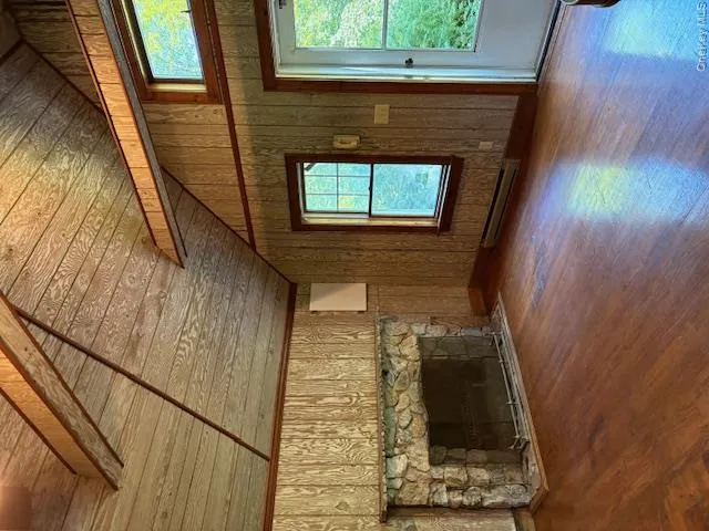 Guest House Unfurnished living room featuring wood walls, plenty of natural light, lofted ceiling, hardwood / wood-style floors, and wooden ceiling Guest House Unfurnished living room featuring wood walls, plenty of natural light, lofted ceiling, hardwood / wood-style floors, and wooden ceiling