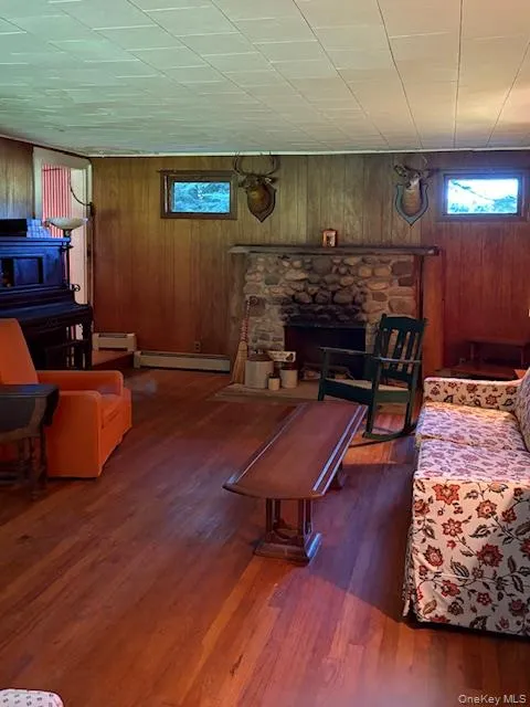 Main House Living room featuring wood walls, a fireplace, dark wood finished floors Main House Living room featuring wood walls, a fireplace, dark wood finished floors