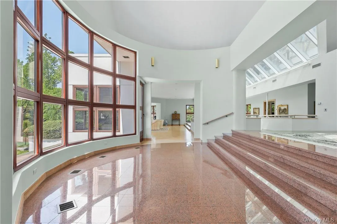 Lower Level of the Entrance Foyer featuring a Wall of Windows overlooking the Beautifully Landscaped Grounds Lower Level of the Entrance Foyer featuring a Wall of Windows overlooking the Beautifully Landscaped Grounds