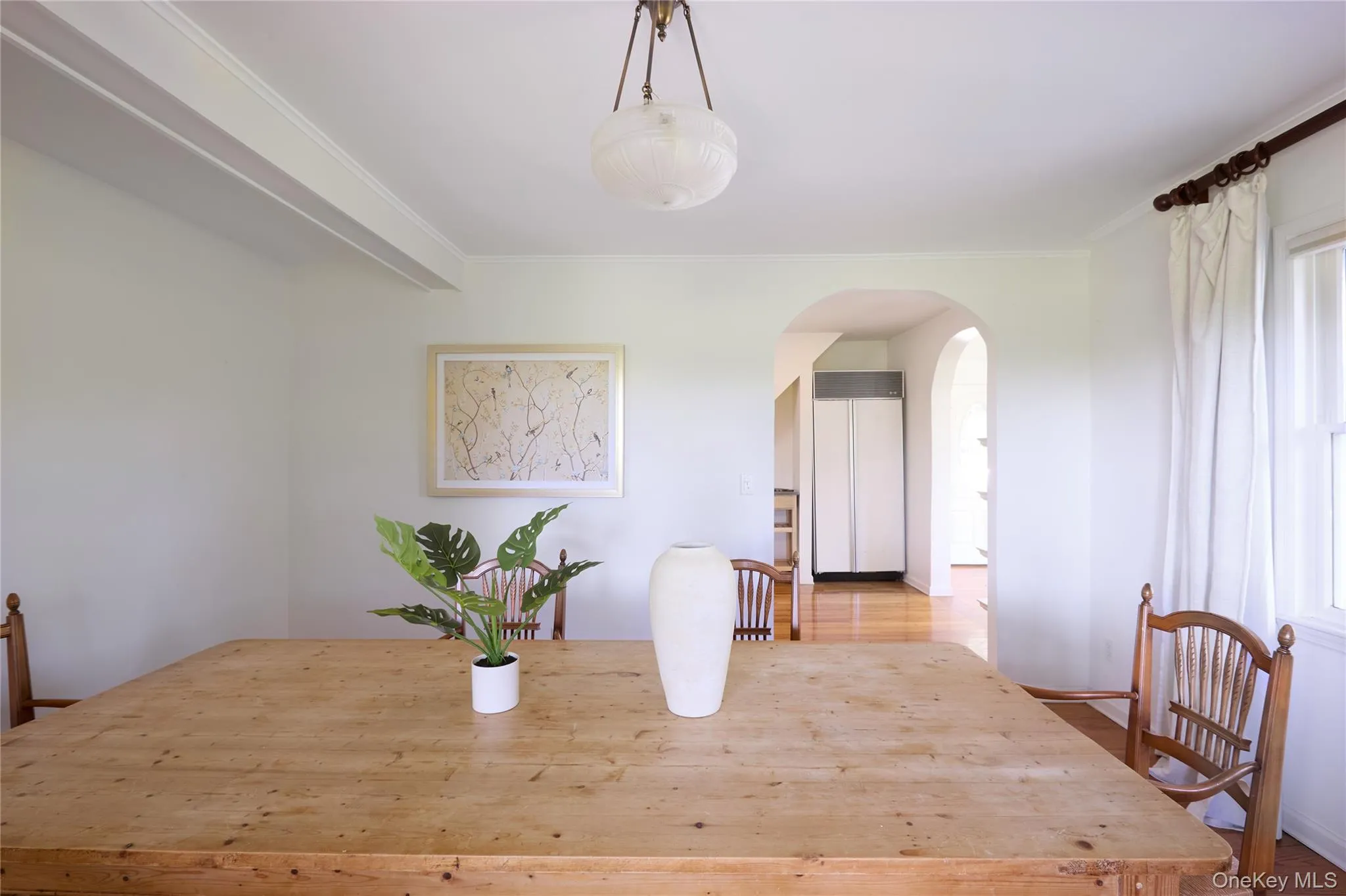 Dining room featuring arched walkways, crown molding, wood finished floors, and beamed ceiling Dining room featuring arched walkways, crown molding, wood finished floors, and beamed ceiling