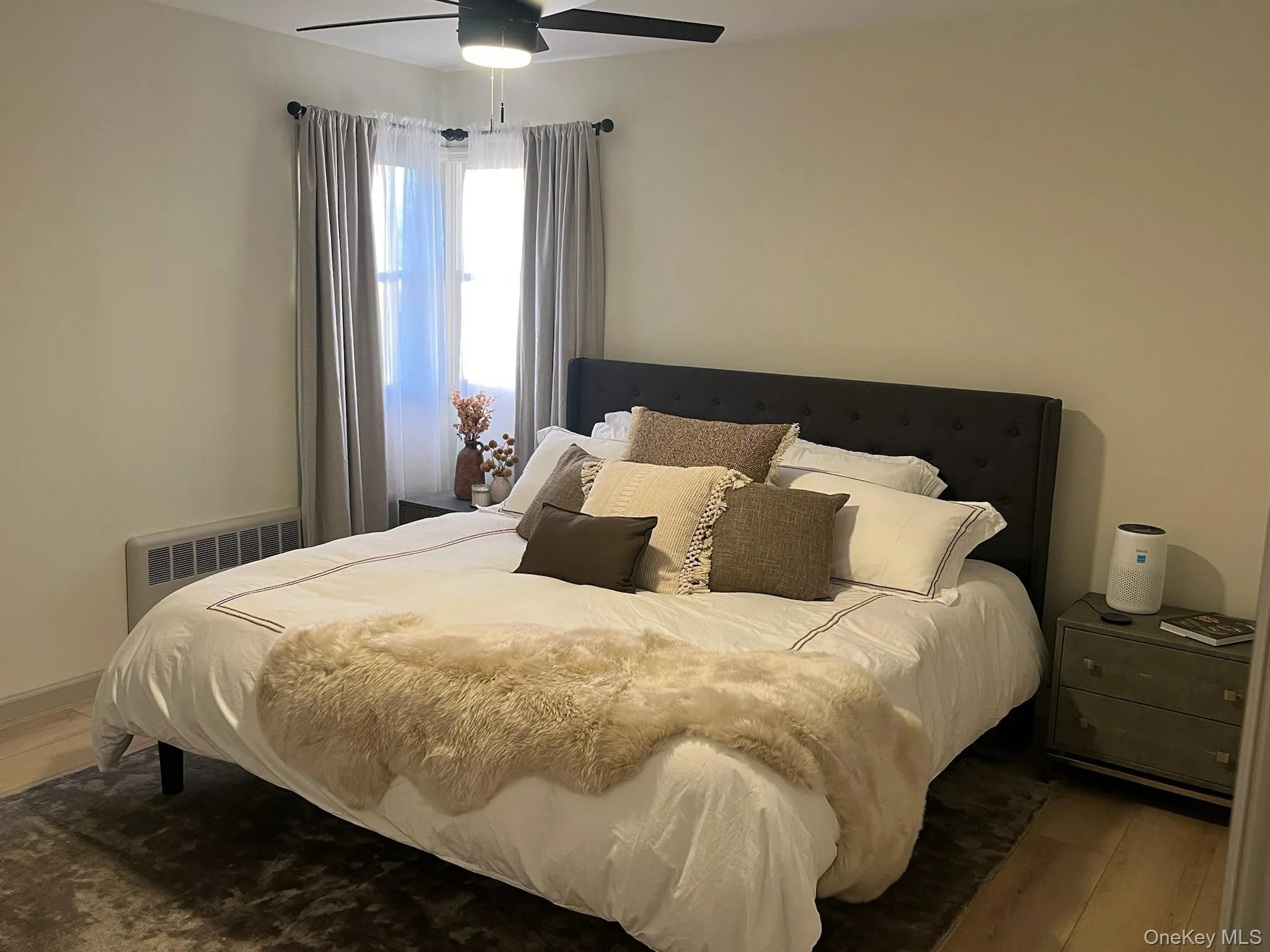 Bedroom with radiator heating unit, wood finished floors, and a ceiling fan Bedroom with radiator heating unit, wood finished floors, and a ceiling fan