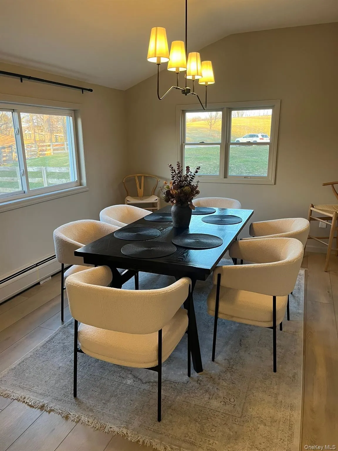 Dining space with a baseboard heating unit, vaulted ceiling, and light wood-type flooring Dining space with a baseboard heating unit, vaulted ceiling, and light wood-type flooring