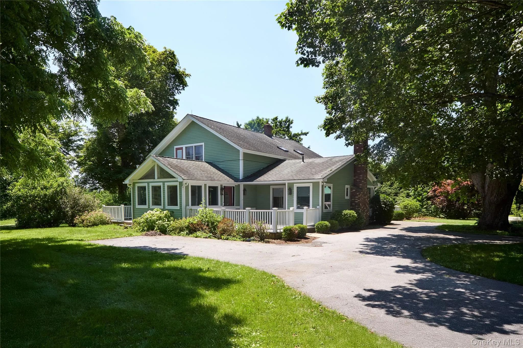 View of front of property with a front yard, driveway, a sunroom, and roof with shingles View of front of property with a front yard, driveway, a sunroom, and roof with shingles