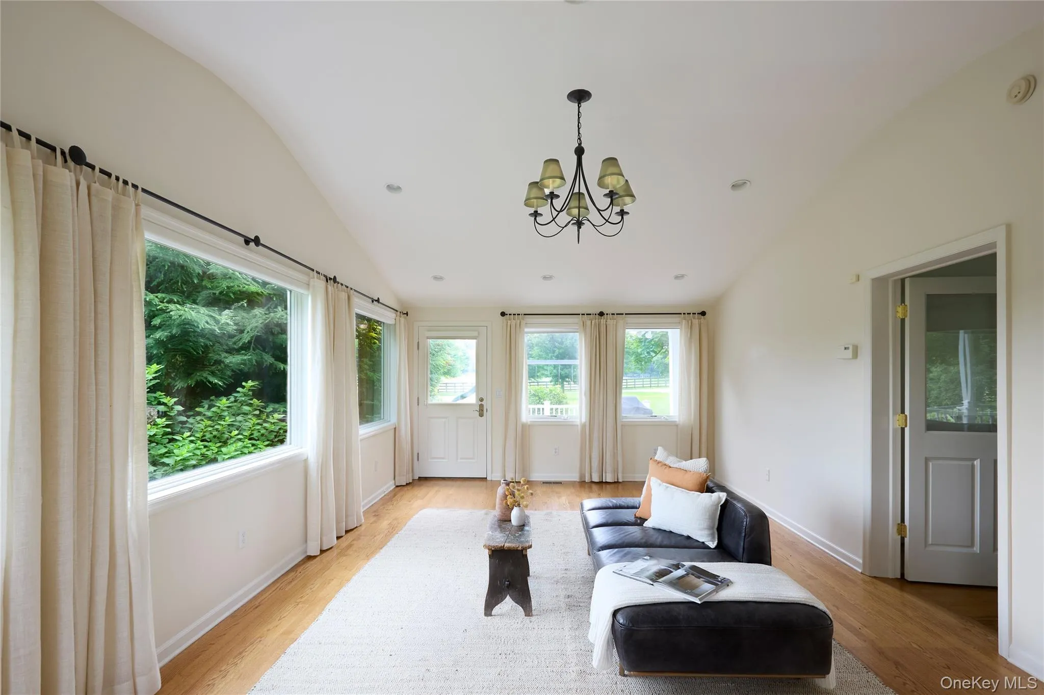 Living area with a chandelier, lofted ceiling, light wood-style floors, and recessed lighting Living area with a chandelier, lofted ceiling, light wood-style floors, and recessed lighting