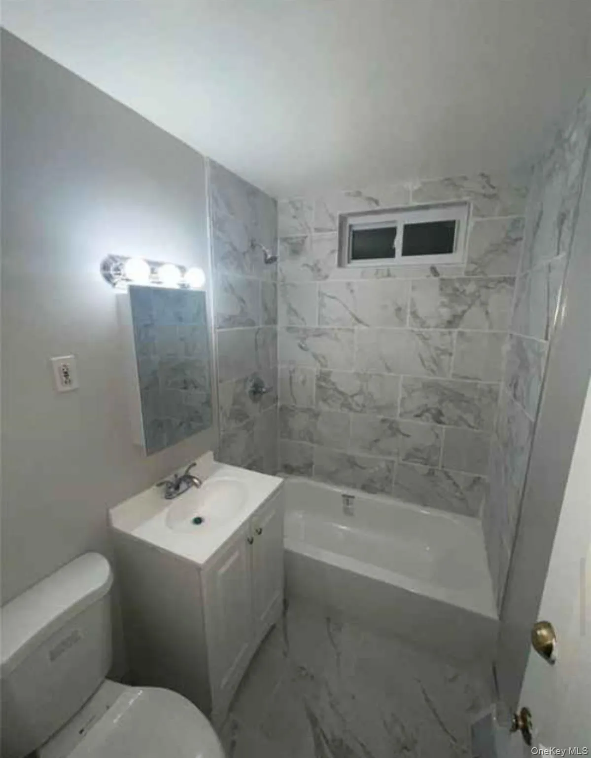 Bathroom featuring shower / tub combination, vanity, and marble look tile flooring Bathroom featuring shower / tub combination, vanity, and marble look tile flooring