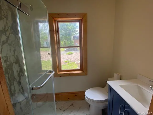 Bathroom with light marble finish floors, vanity, and a stall shower Bathroom with light marble finish floors, vanity, and a stall shower
