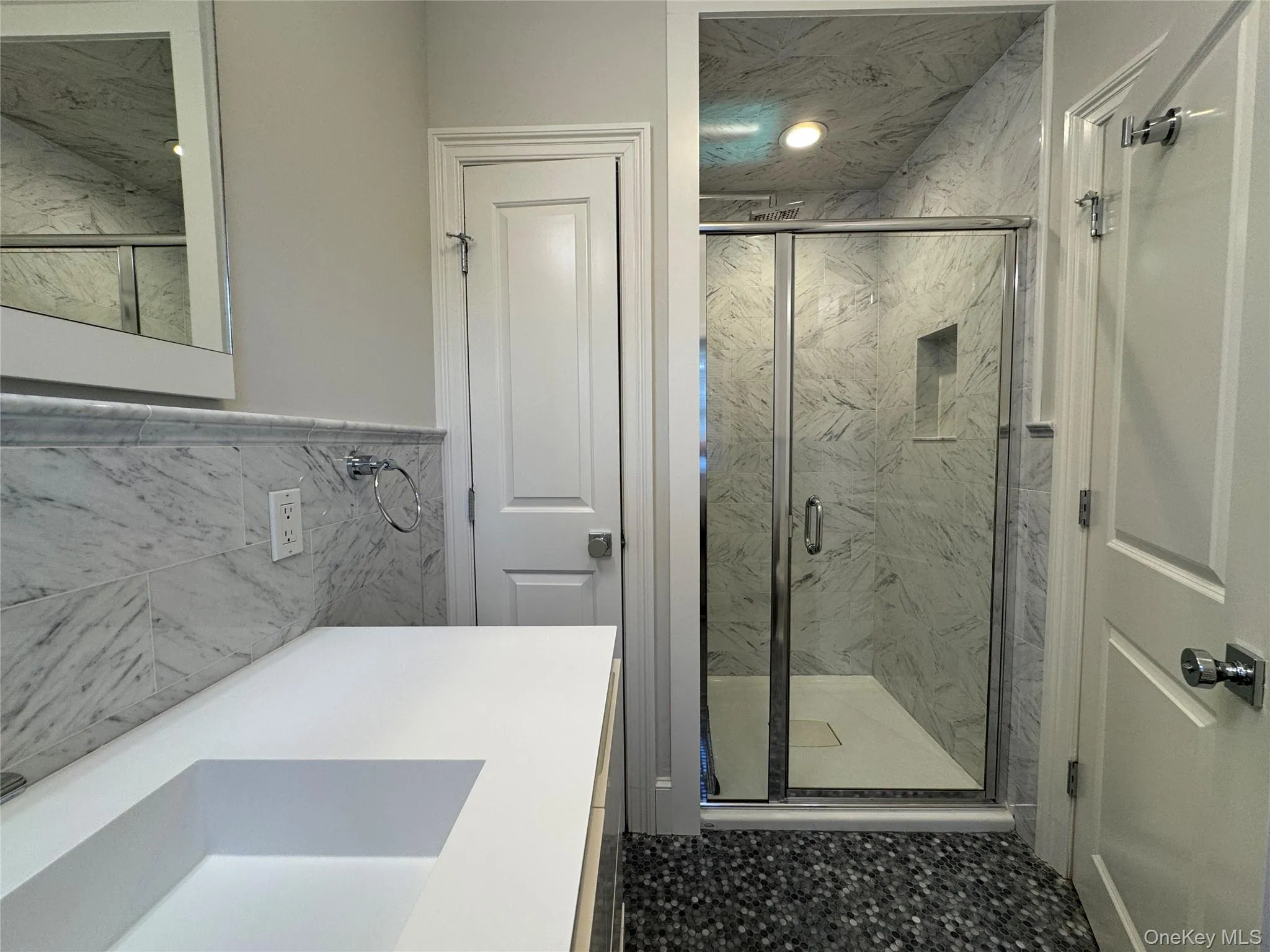 Full bath featuring tile walls, a marble finish shower, and vanity Full bath featuring tile walls, a marble finish shower, and vanity