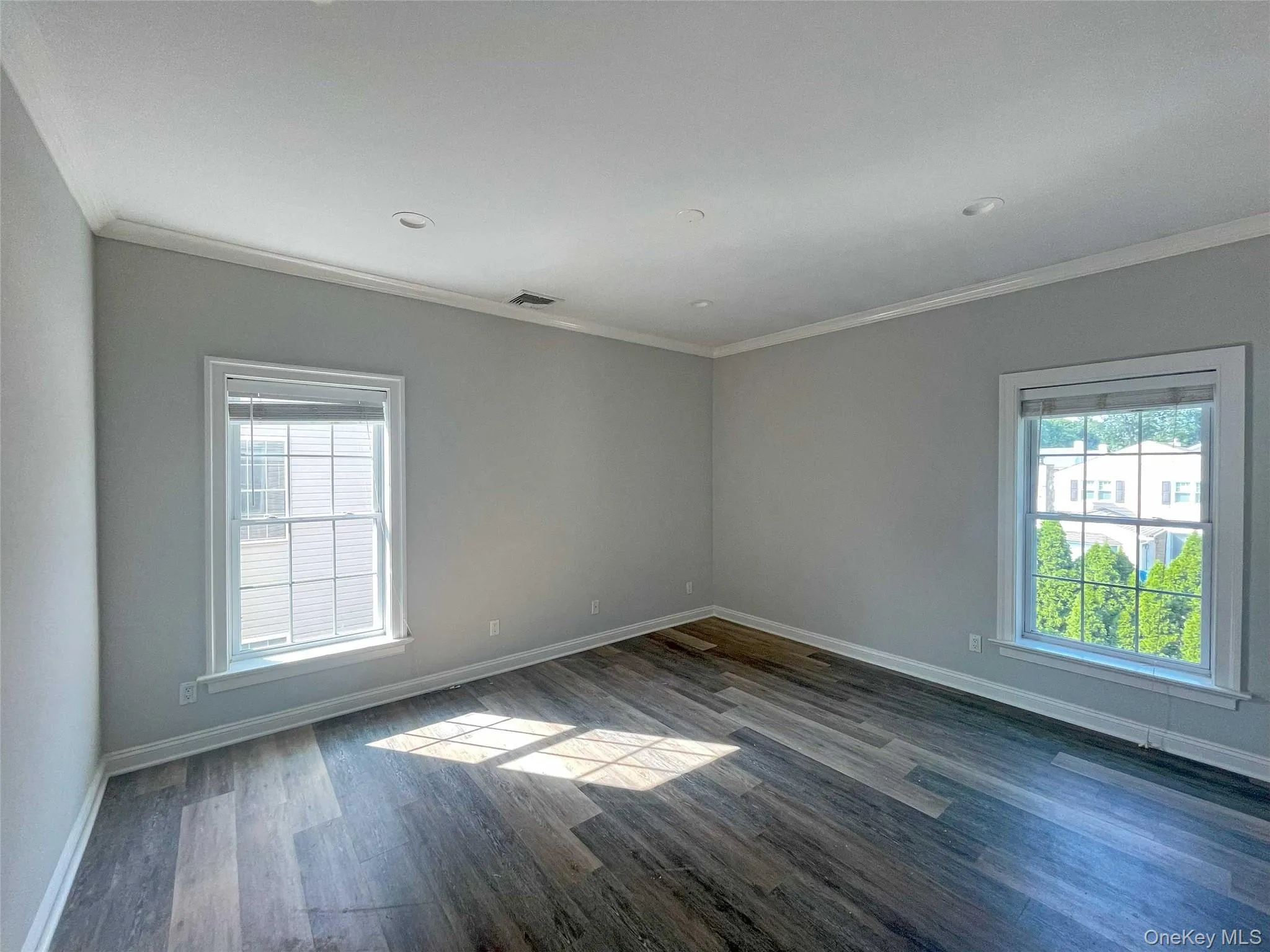 Primary bedroom with ornamental molding, plenty of natural light, and dark wood-type flooring Primary bedroom with ornamental molding, plenty of natural light, and dark wood-type flooring