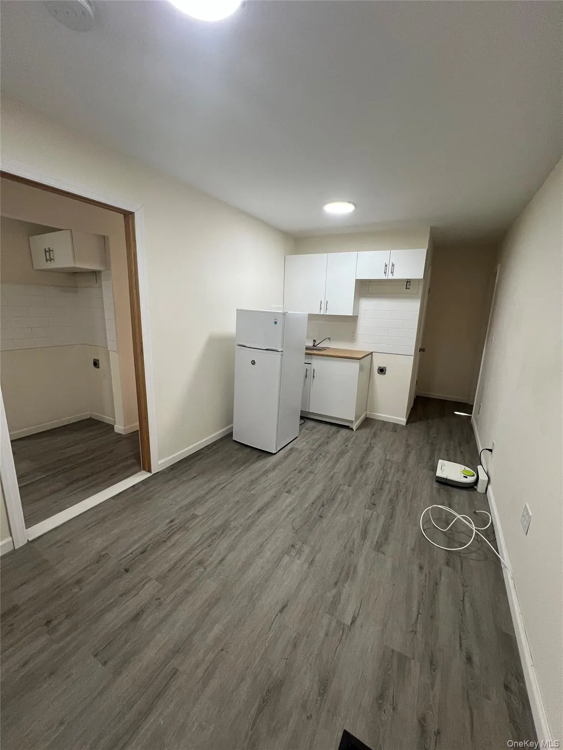 dark wood-type flooring, freestanding refrigerator, white cabinets, and light countertops dark wood-type flooring, freestanding refrigerator, white cabinets, and light countertops