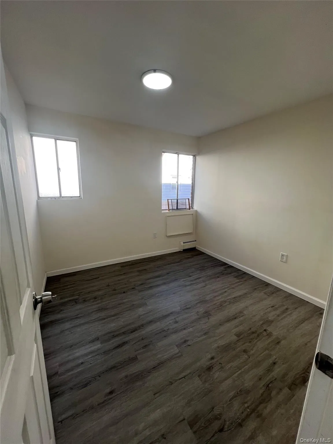 Spare room with dark wood-style flooring and a baseboard heating unit Spare room with dark wood-style flooring and a baseboard heating unit