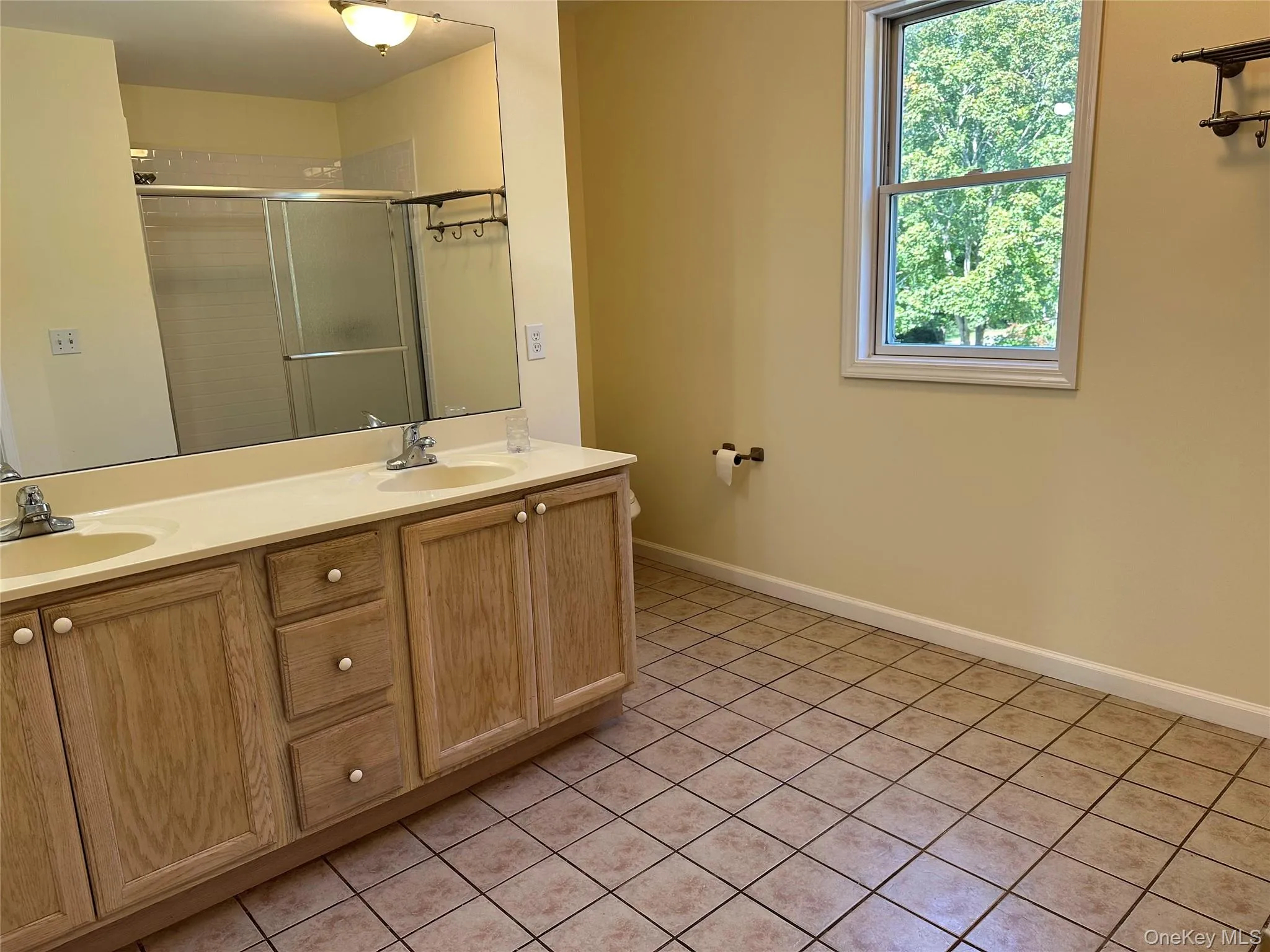 Bathroom featuring double vanity, a shower stall, and light tile patterned floors Bathroom featuring double vanity, a shower stall, and light tile patterned floors
