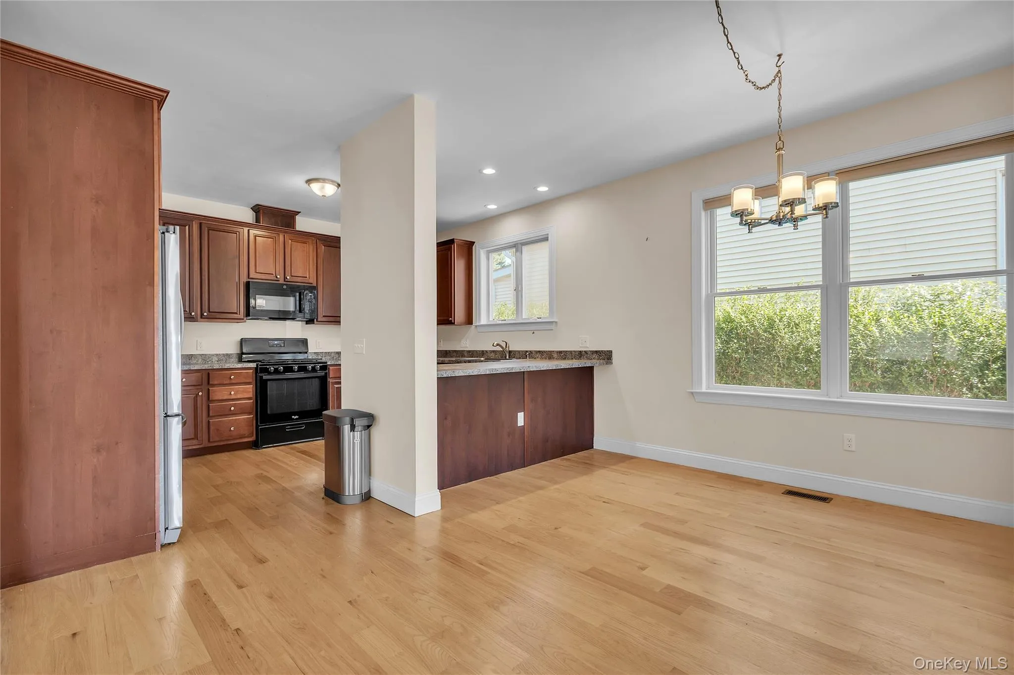 Kitchen with black appliances, hanging light fixtures, light wood-style floors, recessed lighting, and a chandelier Kitchen with black appliances, hanging light fixtures, light wood-style floors, recessed lighting, and a chandelier