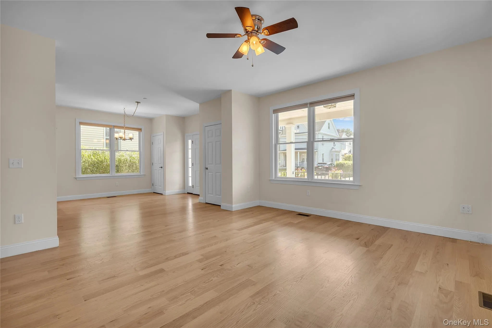 Unfurnished living room featuring a chandelier, light wood-style flooring, and plenty of natural light Unfurnished living room featuring a chandelier, light wood-style flooring, and plenty of natural light