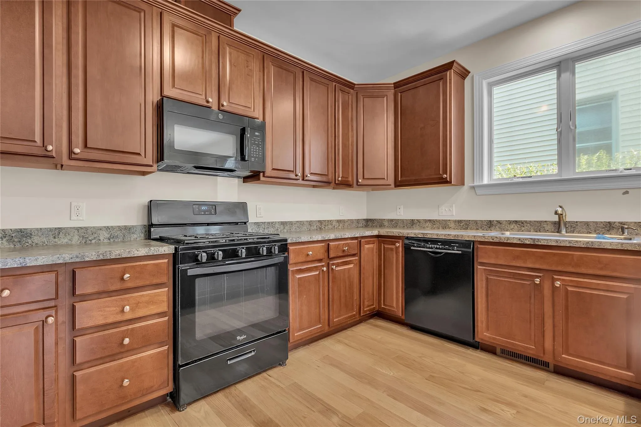 Kitchen featuring black appliances, brown cabinets, and light wood-type flooring Kitchen featuring black appliances, brown cabinets, and light wood-type flooring