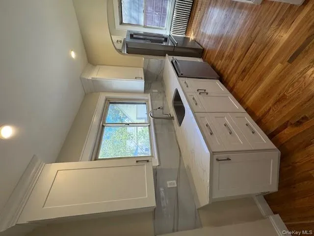 Kitchen with white cabinetry, dark wood-type flooring, light stone counters, backsplash, and recessed lighting Kitchen with white cabinetry, dark wood-type flooring, light stone counters, backsplash, and recessed lighting