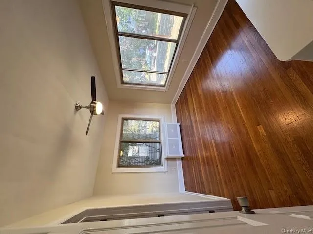 Unfurnished room featuring dark wood-type flooring, healthy amount of natural light, radiator, and a ceiling fan Unfurnished room featuring dark wood-type flooring, healthy amount of natural light, radiator, and a ceiling fan