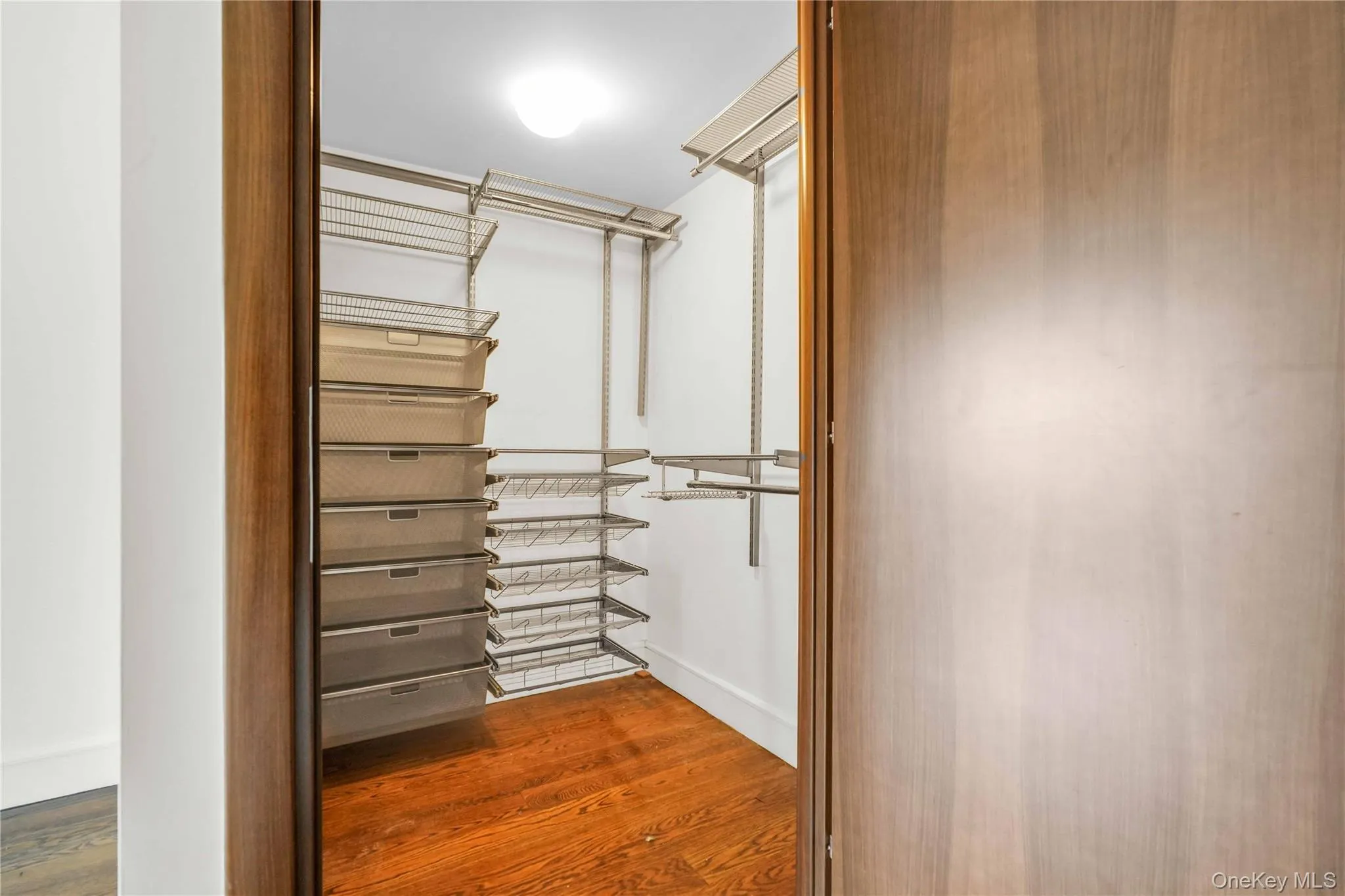 Walk in closet featuring dark wood-style floors Walk in closet featuring dark wood-style floors