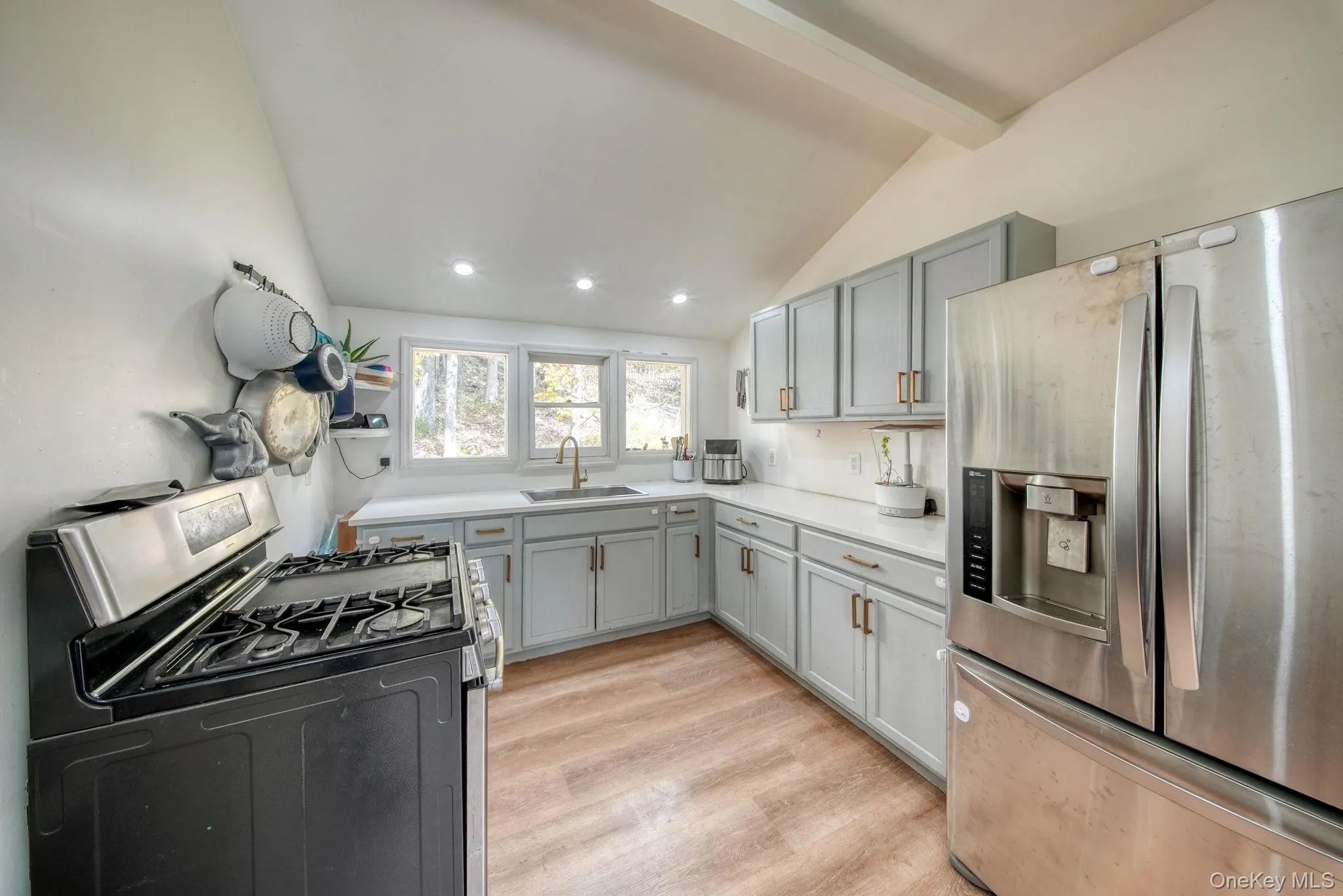 Kitchen with gray cabinetry, appliances with stainless steel finishes, open shelves, light wood-style floors, and recessed lighting Kitchen with gray cabinetry, appliances with stainless steel finishes, open shelves, light wood-style floors, and recessed lighting