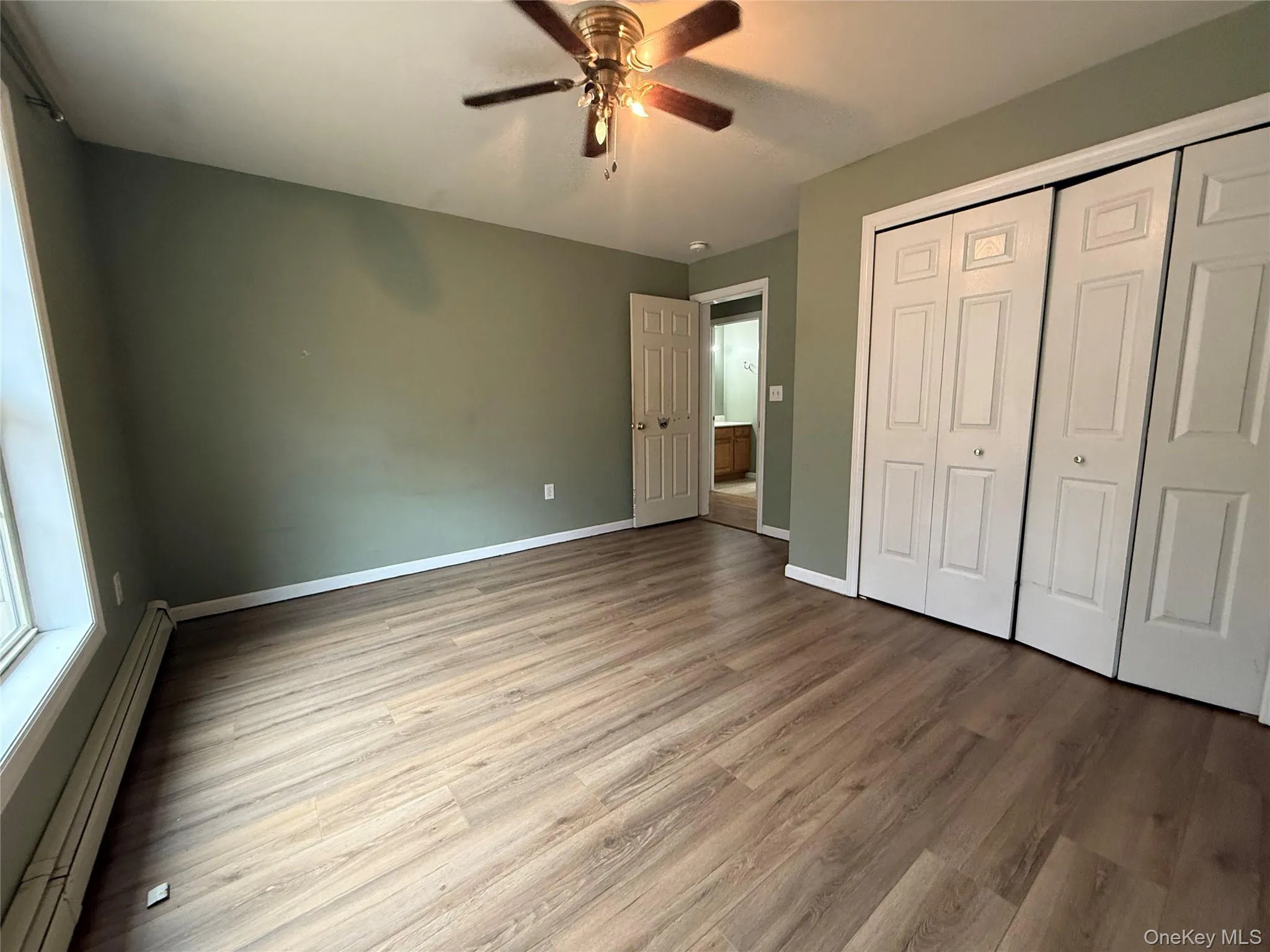 Unfurnished bedroom with a baseboard heating unit, a closet, light wood-type flooring, and ceiling fan Unfurnished bedroom with a baseboard heating unit, a closet, light wood-type flooring, and ceiling fan