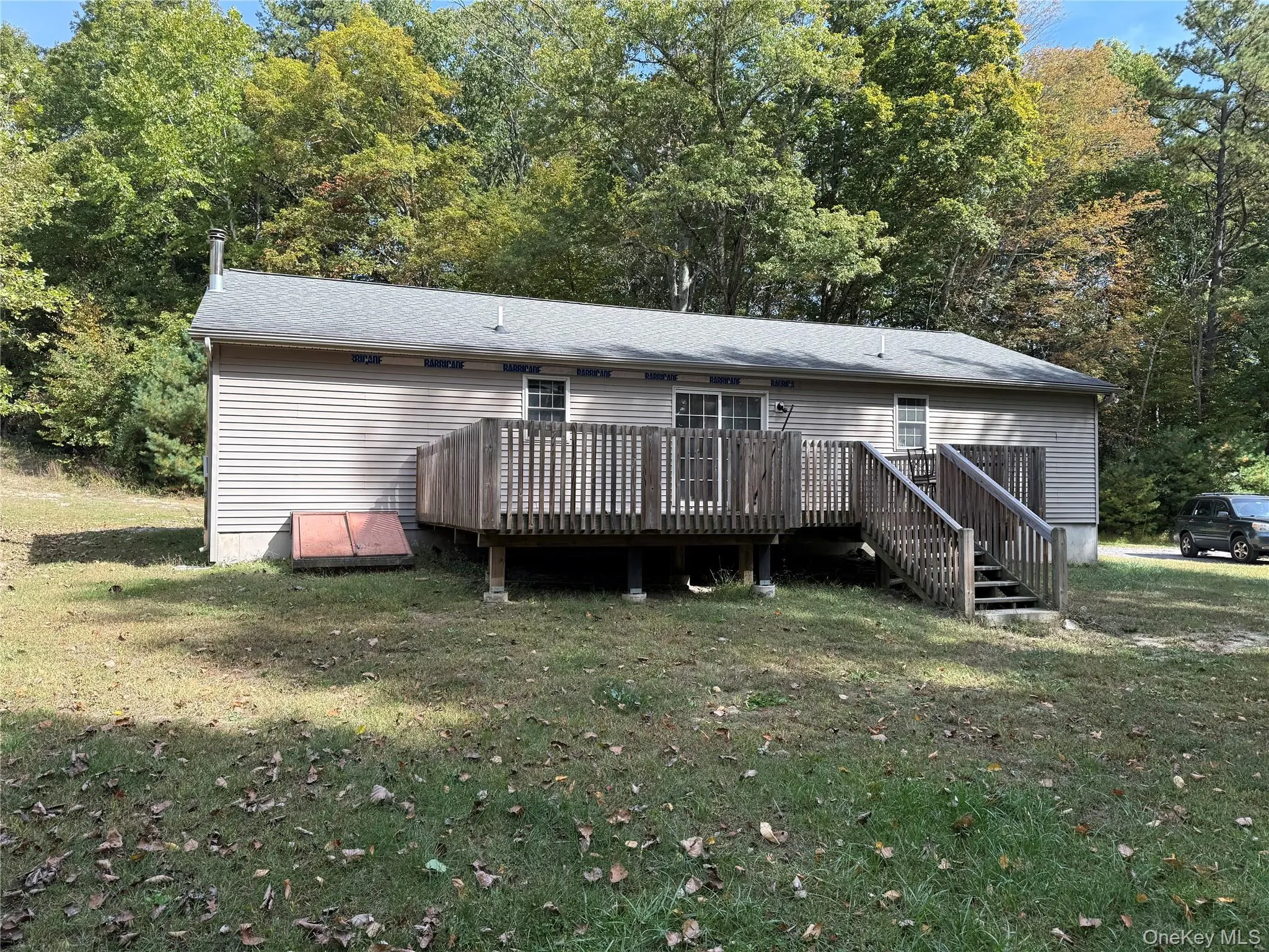 Rear view of property featuring a yard, a wooden deck, and a shingled roof Rear view of property featuring a yard, a wooden deck, and a shingled roof