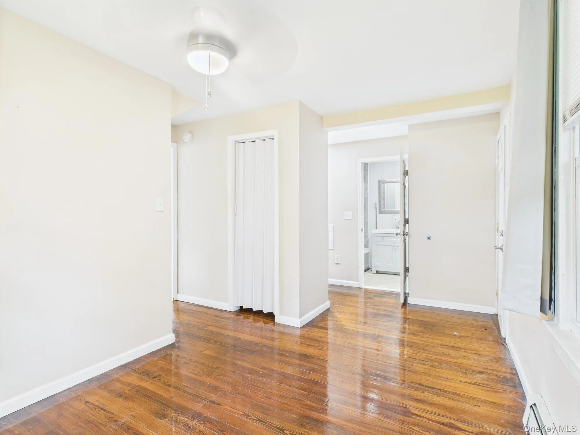 Unfurnished room featuring wood finished floors and a baseboard radiator Unfurnished room featuring wood finished floors and a baseboard radiator