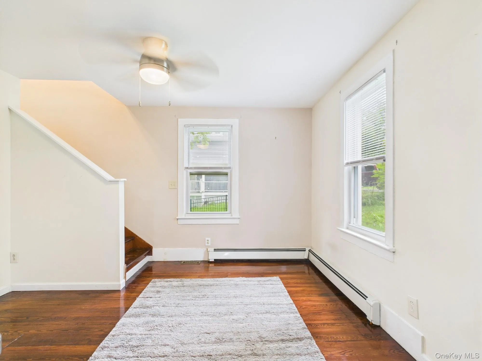 Empty room with plenty of natural light, a baseboard radiator, and dark wood-style flooring Empty room with plenty of natural light, a baseboard radiator, and dark wood-style flooring