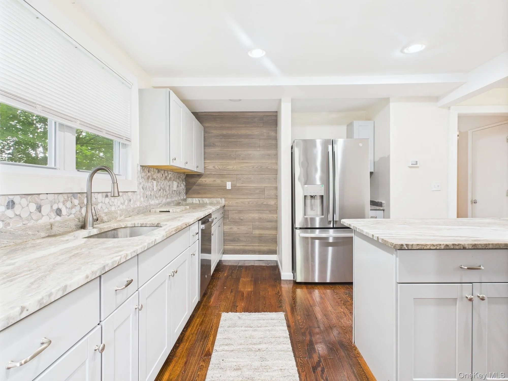 Kitchen featuring stainless steel appliances, dark wood-type flooring, light stone counters, decorative backsplash, and recessed lighting Kitchen featuring stainless steel appliances, dark wood-type flooring, light stone counters, decorative backsplash, and recessed lighting