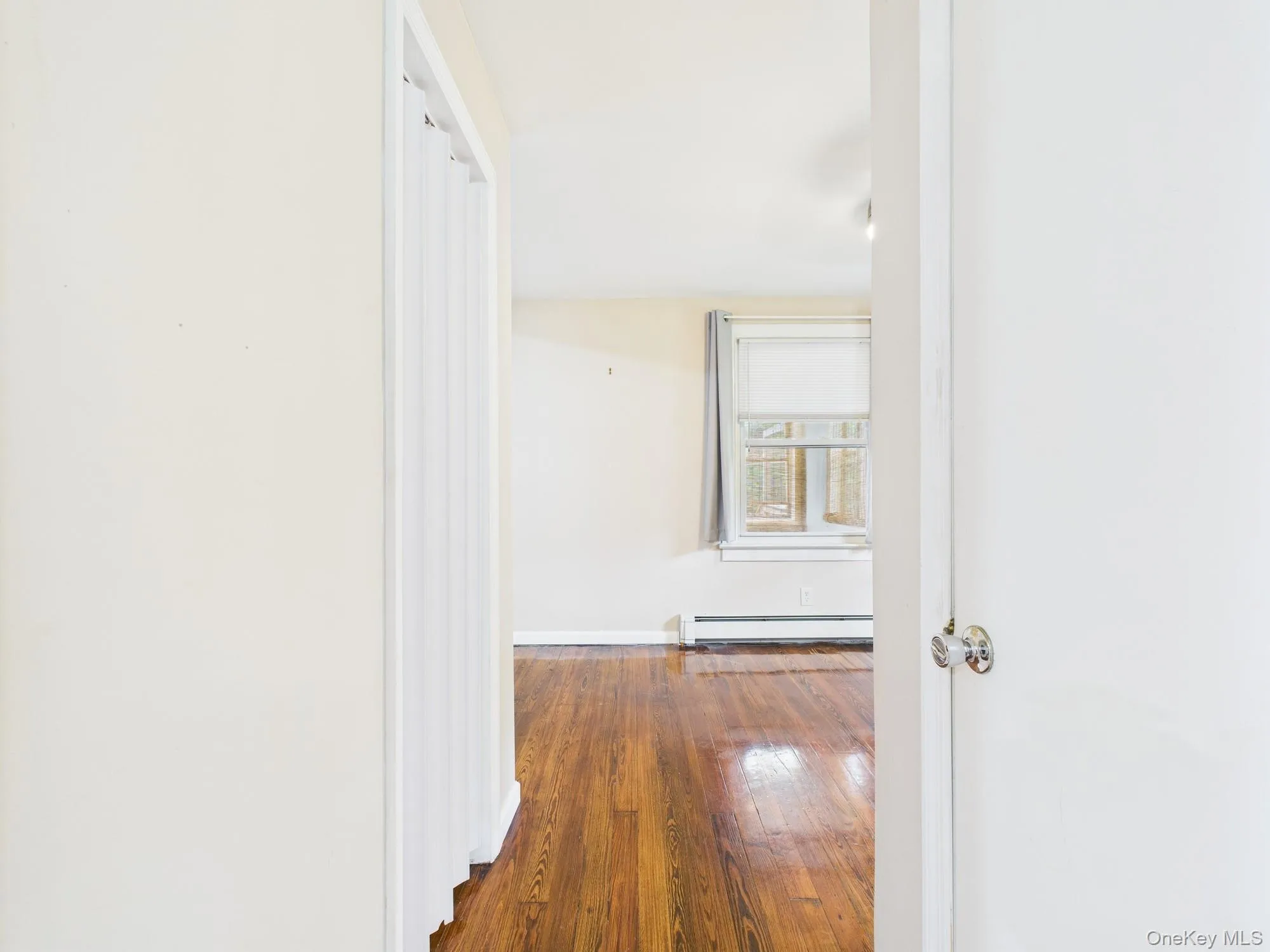 Hall featuring a baseboard radiator and wood-type flooring Hall featuring a baseboard radiator and wood-type flooring