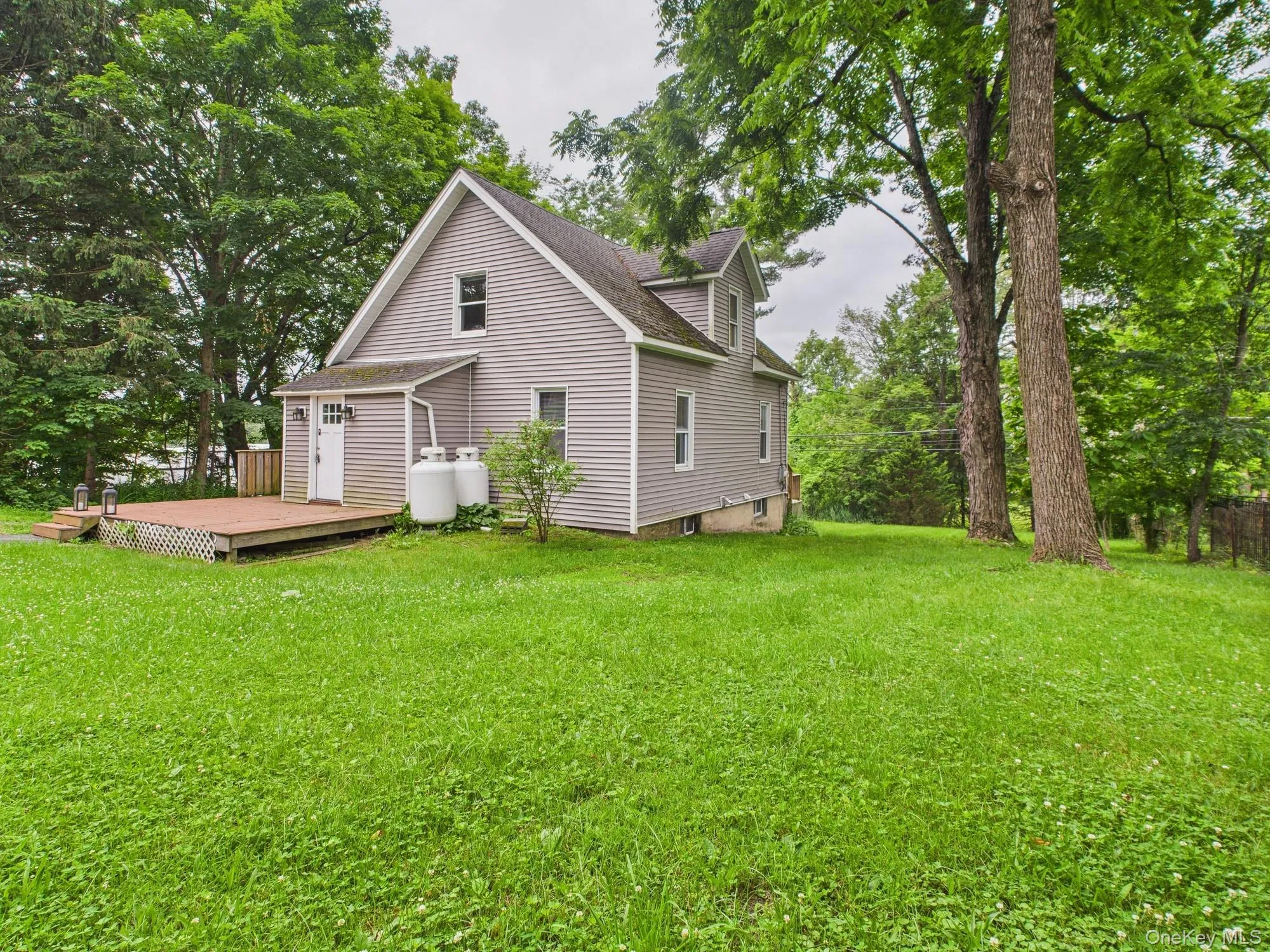 Back of house featuring a deck, a yard, and a shingled roof Back of house featuring a deck, a yard, and a shingled roof
