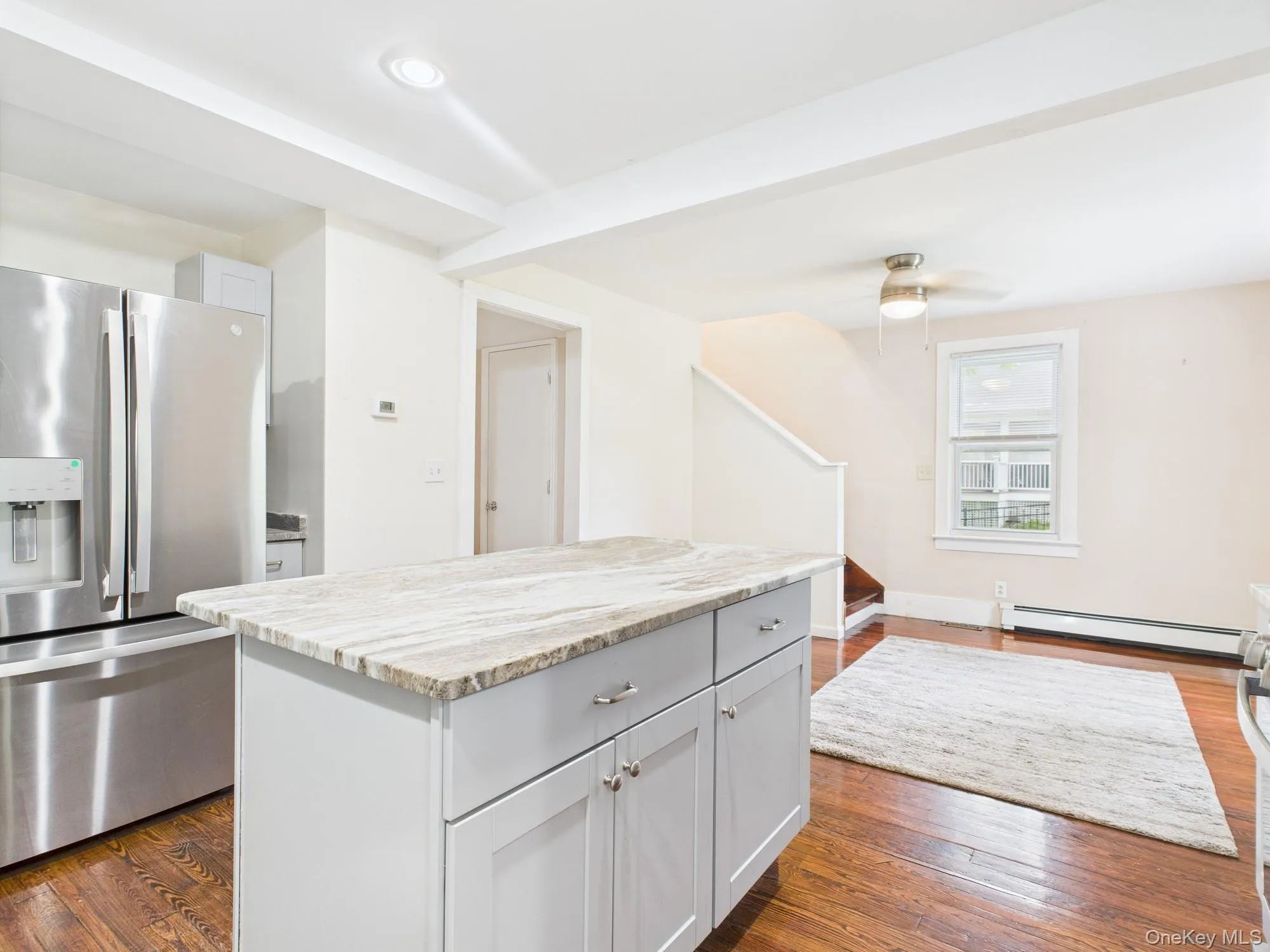 Kitchen with stainless steel fridge, a baseboard heating unit, a center island, dark wood-type flooring, and recessed lighting Kitchen with stainless steel fridge, a baseboard heating unit, a center island, dark wood-type flooring, and recessed lighting