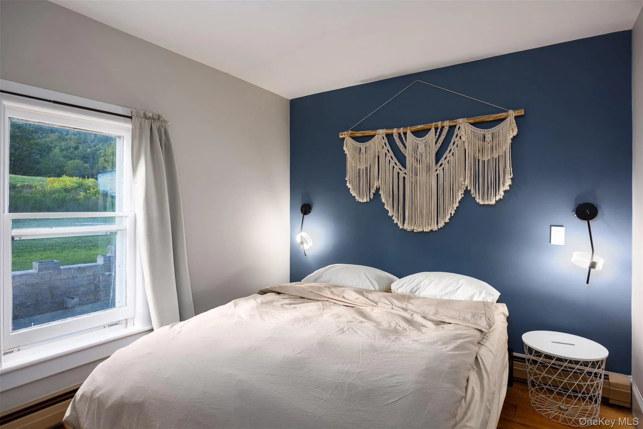 Bedroom featuring wood finished floors and baseboard heating Bedroom featuring wood finished floors and baseboard heating