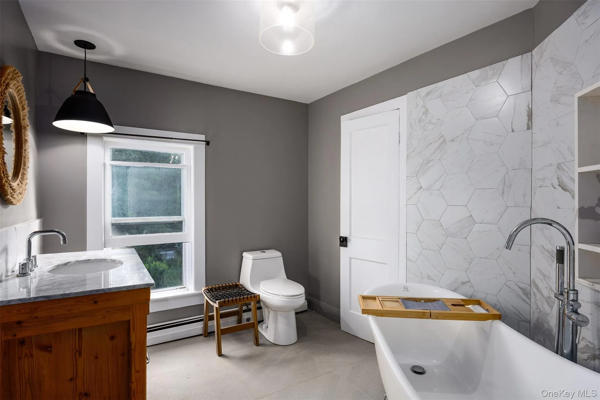 Bathroom featuring a soaking tub, double vanity, tile walls, and baseboard heating Bathroom featuring a soaking tub, double vanity, tile walls, and baseboard heating