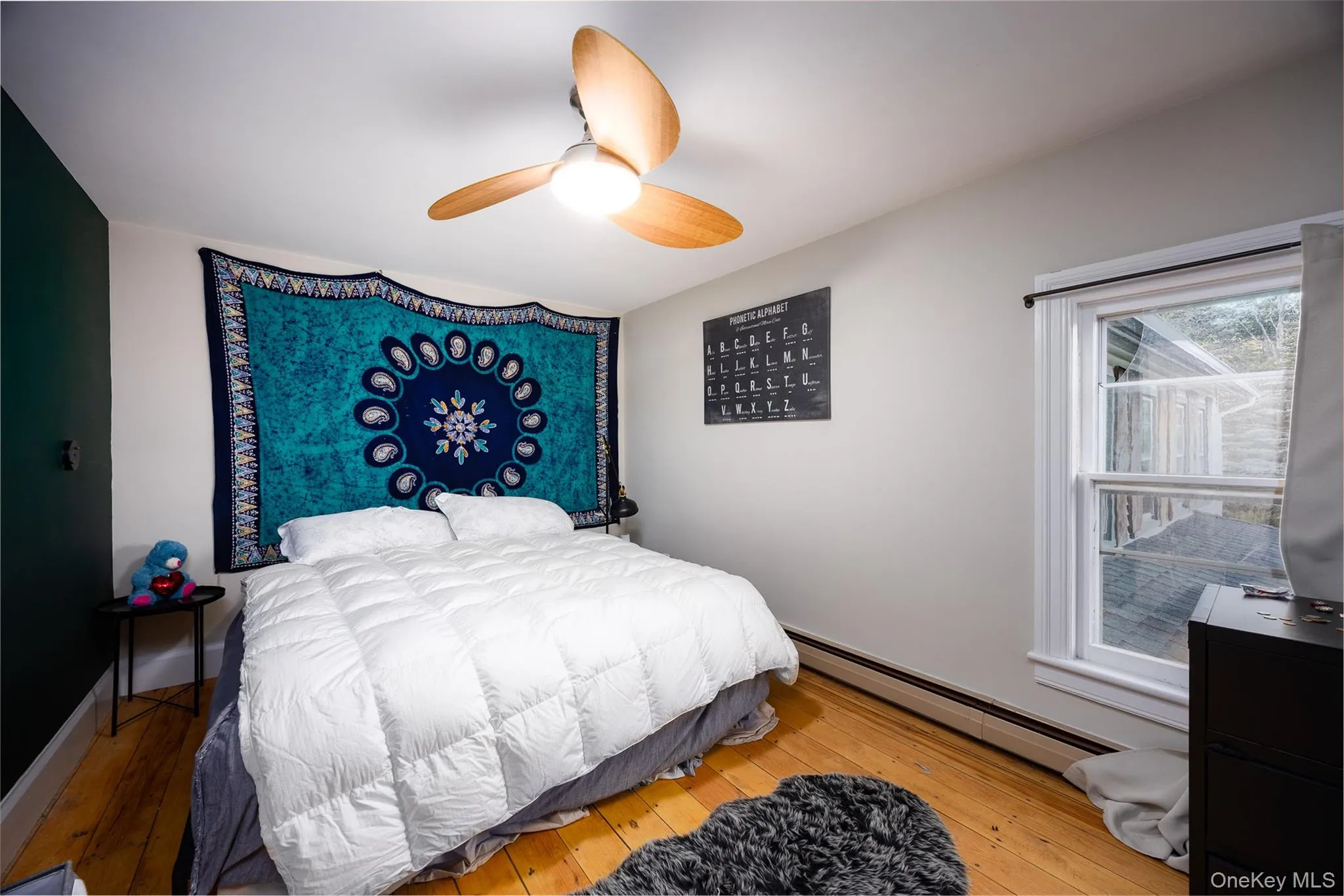 Bedroom featuring baseboard heating, hardwood / wood-style flooring, and ceiling fan Bedroom featuring baseboard heating, hardwood / wood-style flooring, and ceiling fan