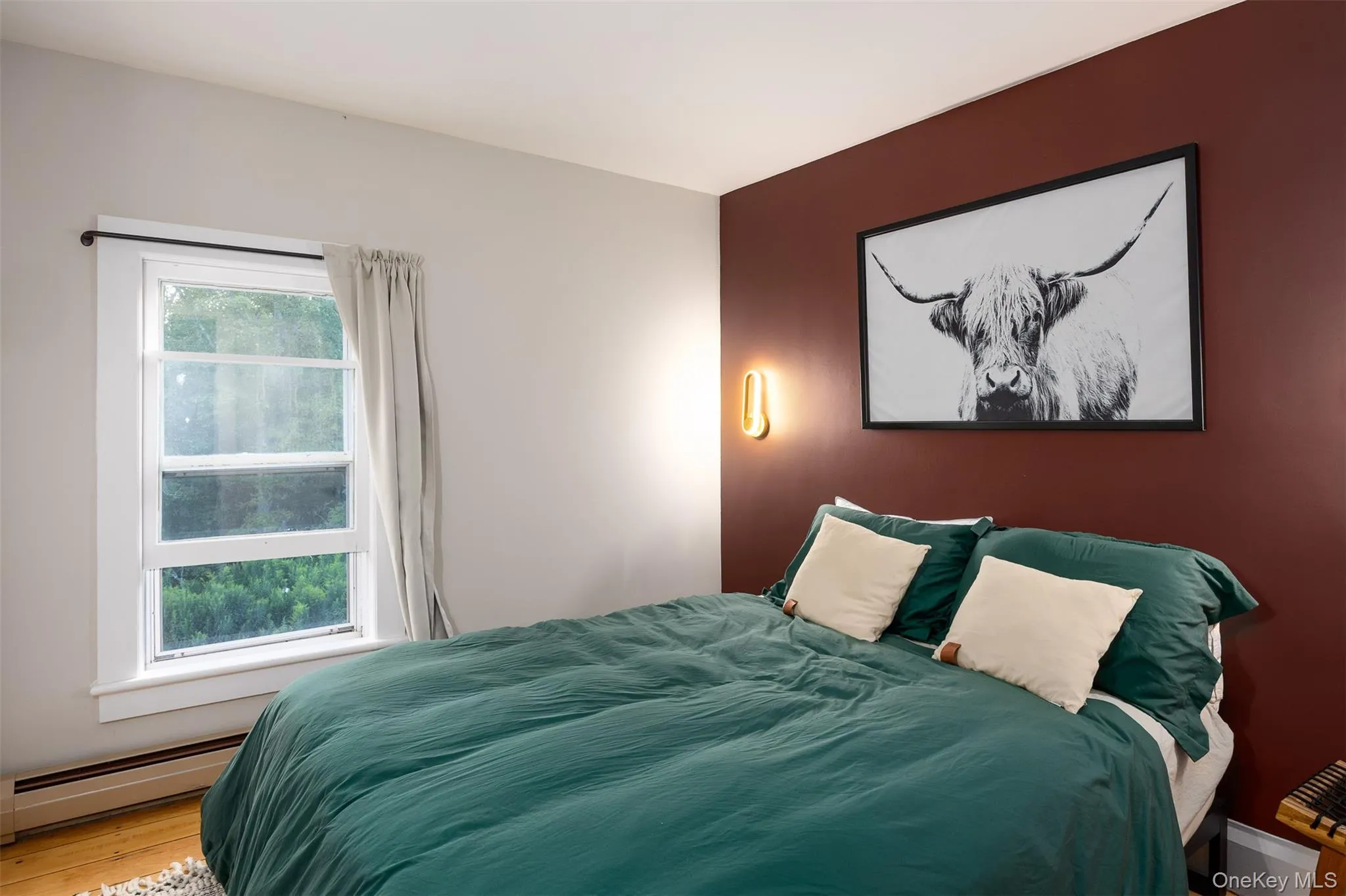 Bedroom featuring a baseboard radiator and wood finished floors Bedroom featuring a baseboard radiator and wood finished floors