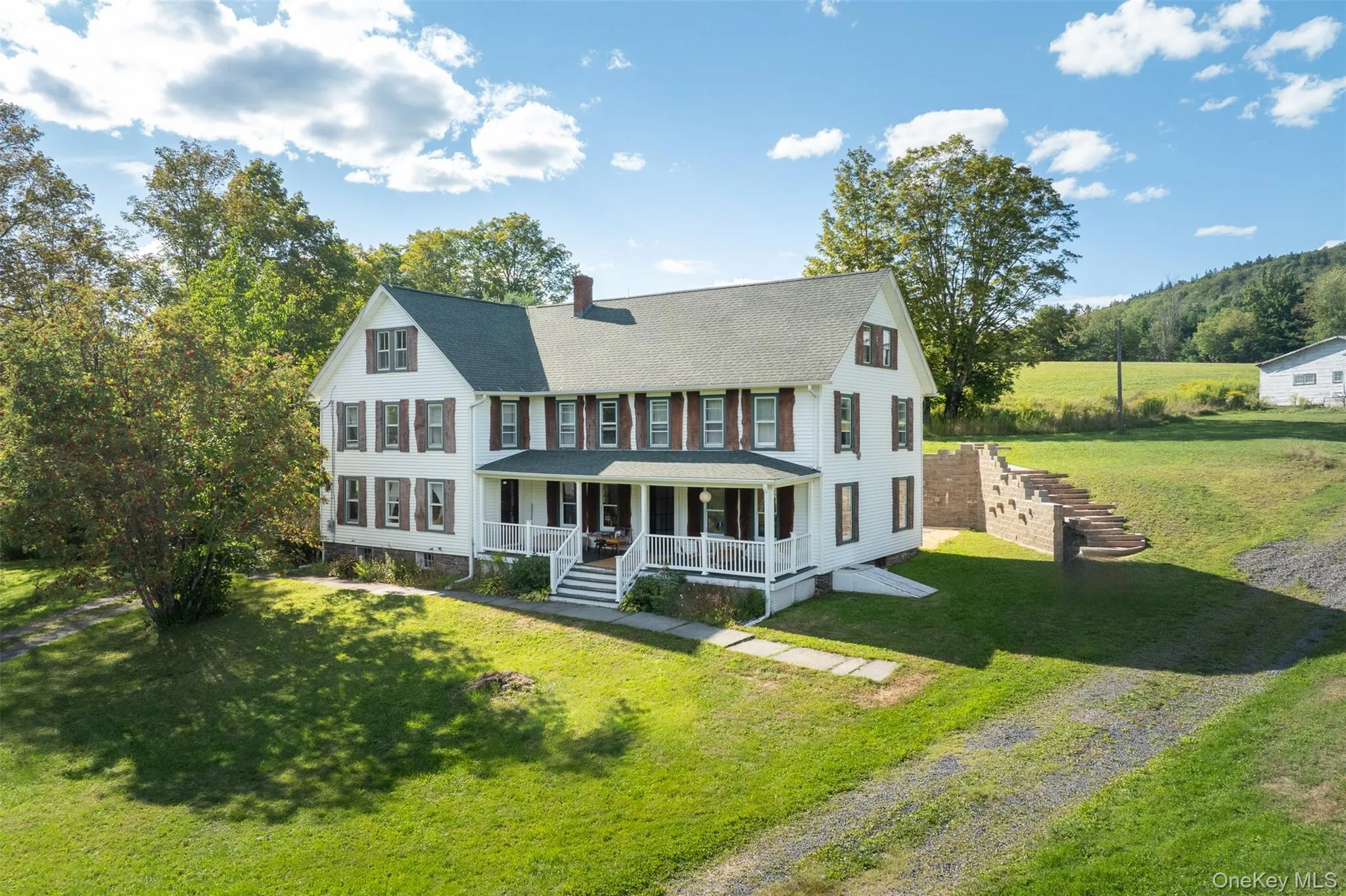 Colonial home featuring covered porch, a chimney, a front lawn, and roof with shingles Colonial home featuring covered porch, a chimney, a front lawn, and roof with shingles