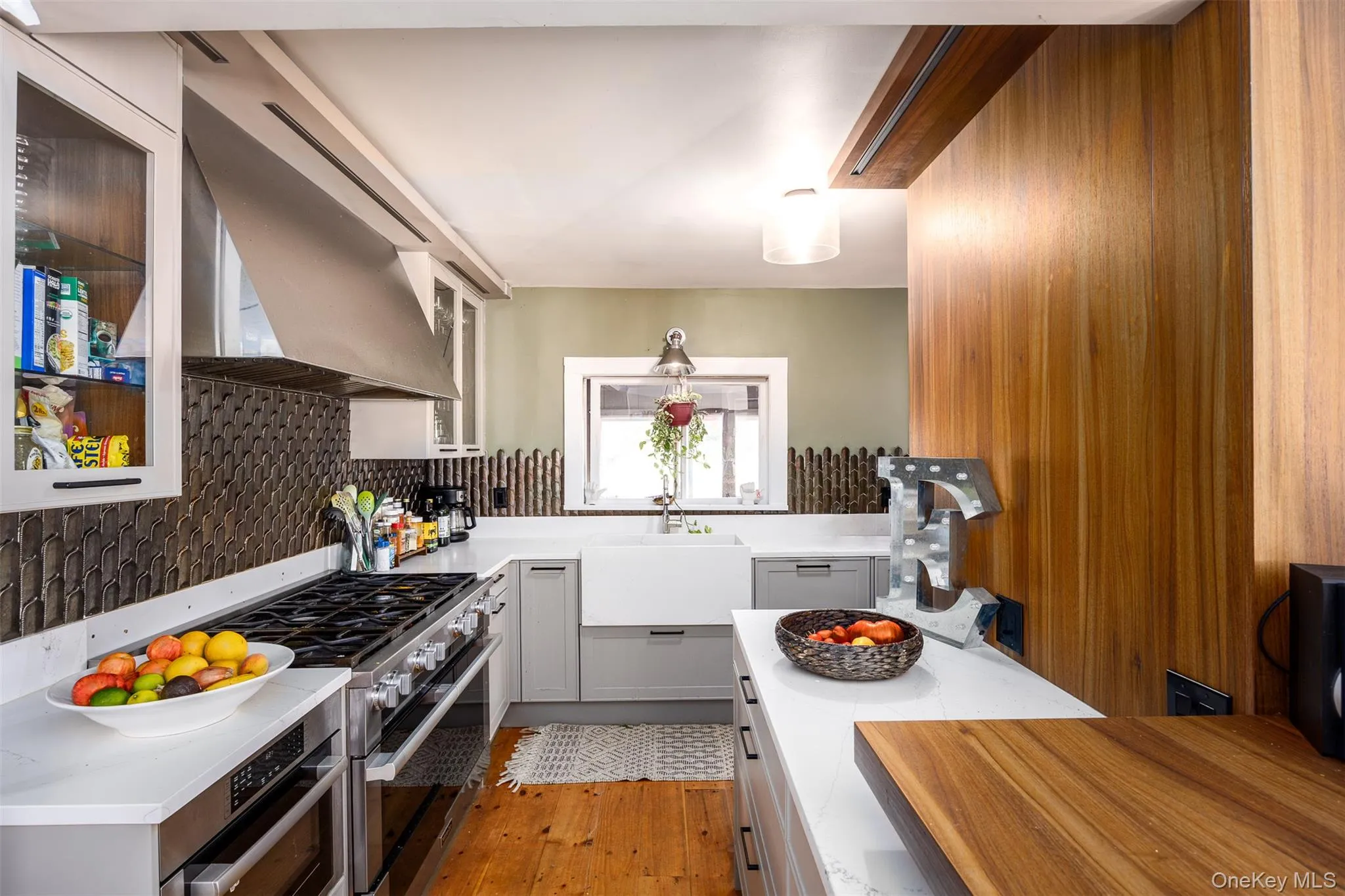Kitchen featuring exhaust hood, stainless steel appliances, light wood-style floors, and light stone counters Kitchen featuring exhaust hood, stainless steel appliances, light wood-style floors, and light stone counters