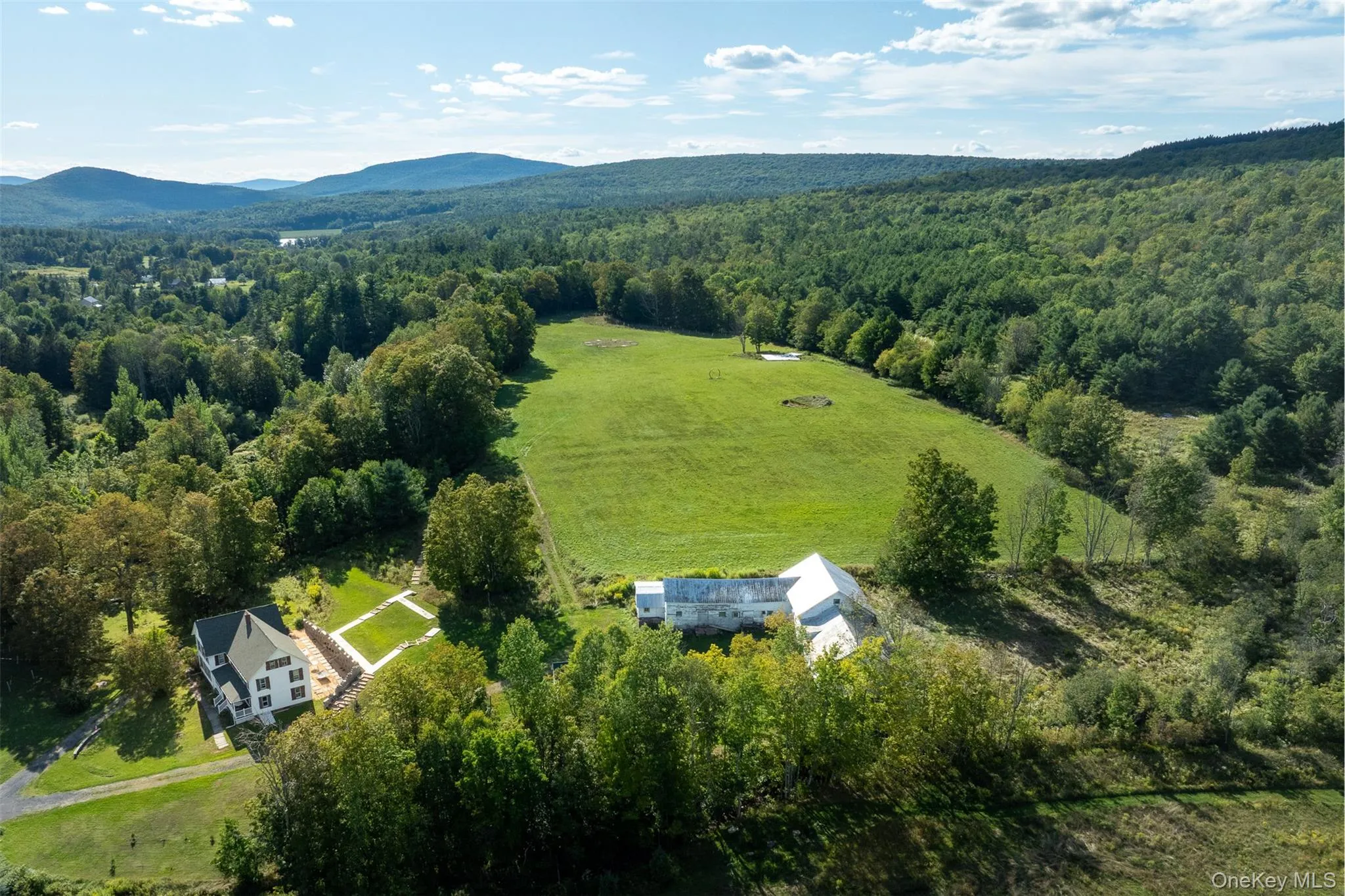 Aerial view of sparsely populated area featuring a heavily wooded area and a mountain backdrop Aerial view of sparsely populated area featuring a heavily wooded area and a mountain backdrop