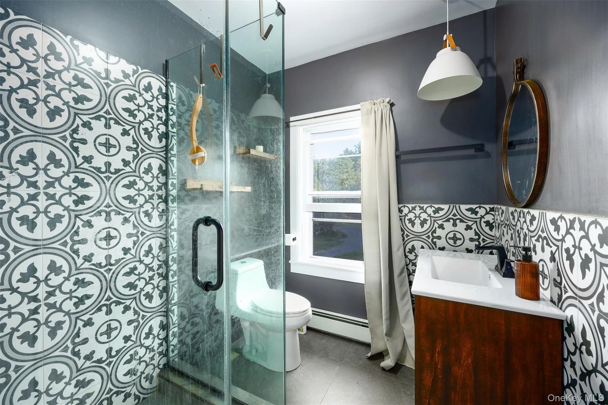 Full bath with vanity, a shower stall, tile patterned floors, a baseboard heating unit, and tile walls Full bath with vanity, a shower stall, tile patterned floors, a baseboard heating unit, and tile walls