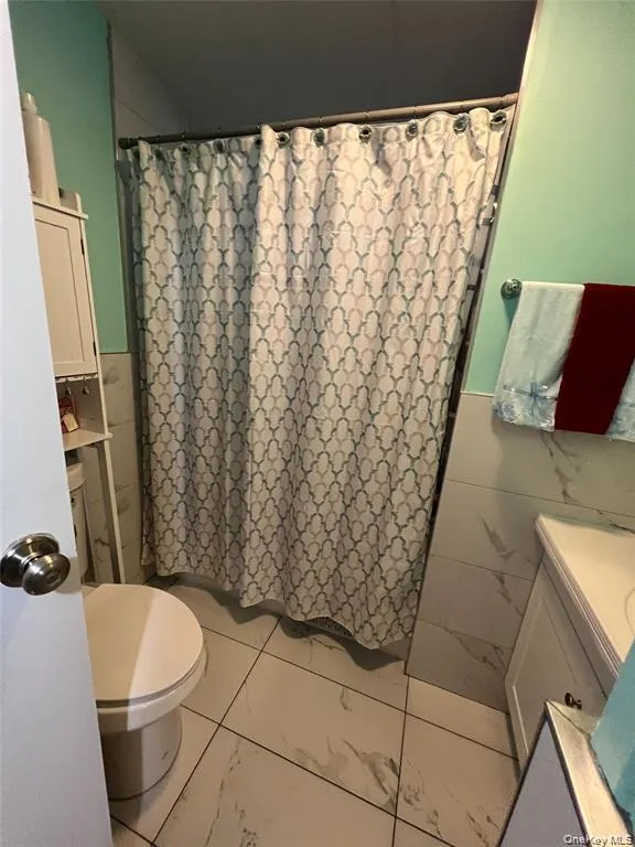 Bathroom featuring vanity, curtained shower, and tile walls Bathroom featuring vanity, curtained shower, and tile walls