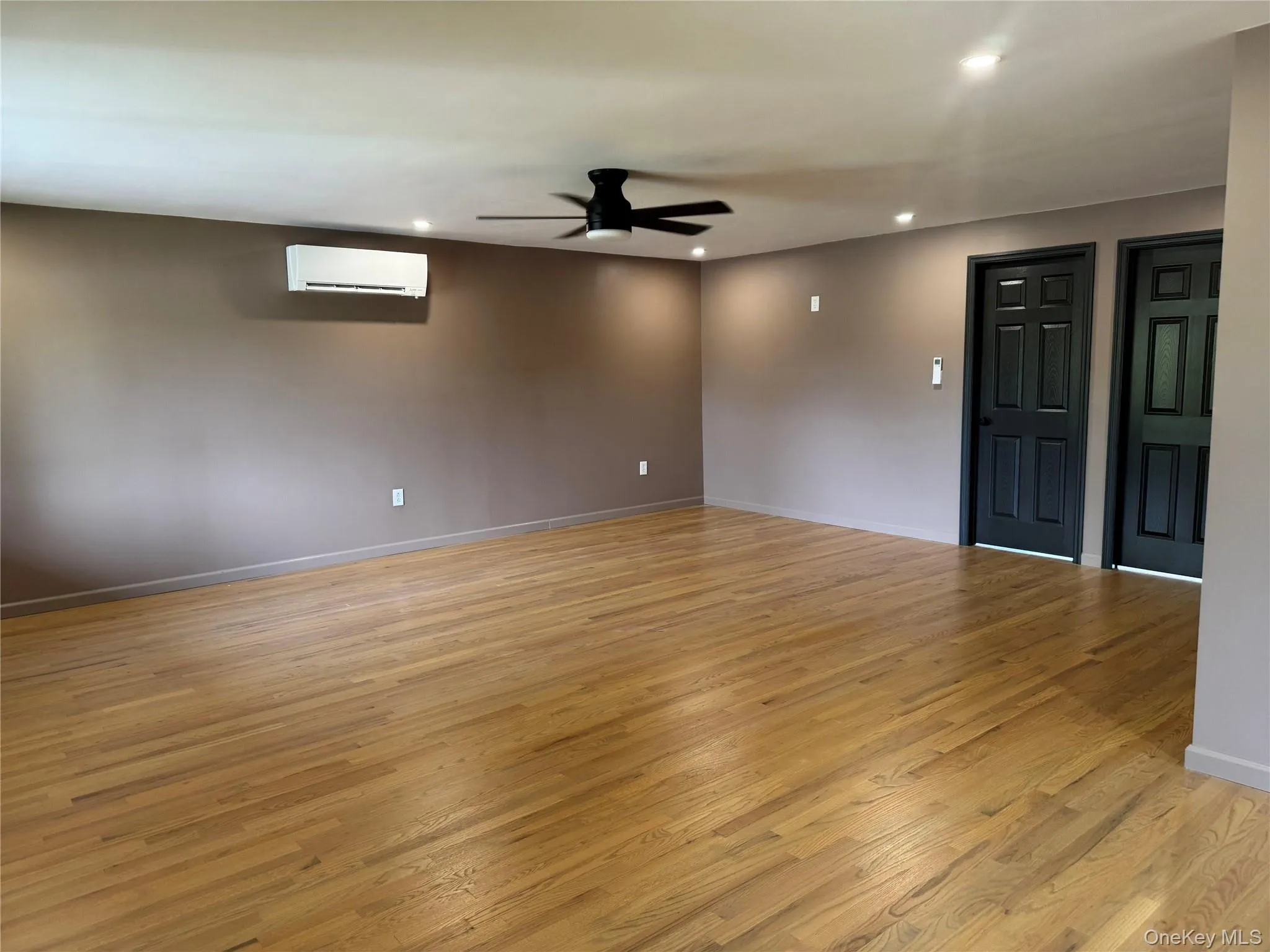 Empty room featuring recessed lighting, light wood-style floors, a ceiling fan, and a wall mounted AC Empty room featuring recessed lighting, light wood-style floors, a ceiling fan, and a wall mounted AC