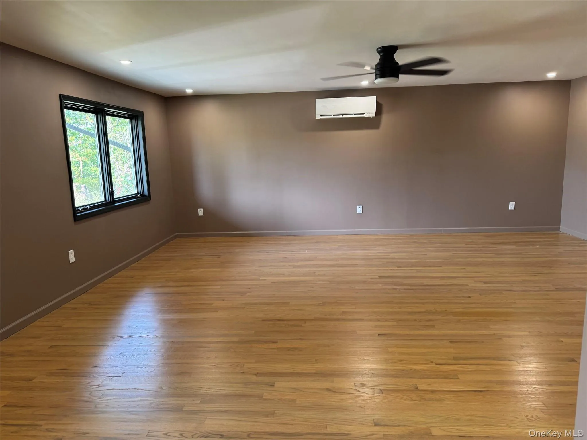 Unfurnished room with recessed lighting, light wood-style flooring, ceiling fan, and a wall mounted air conditioner Unfurnished room with recessed lighting, light wood-style flooring, ceiling fan, and a wall mounted air conditioner