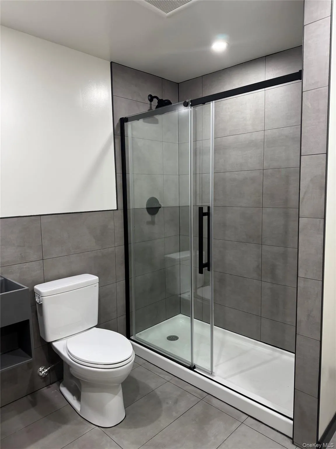 Full bath with a shower stall, tile walls, and tile patterned floors Full bath with a shower stall, tile walls, and tile patterned floors