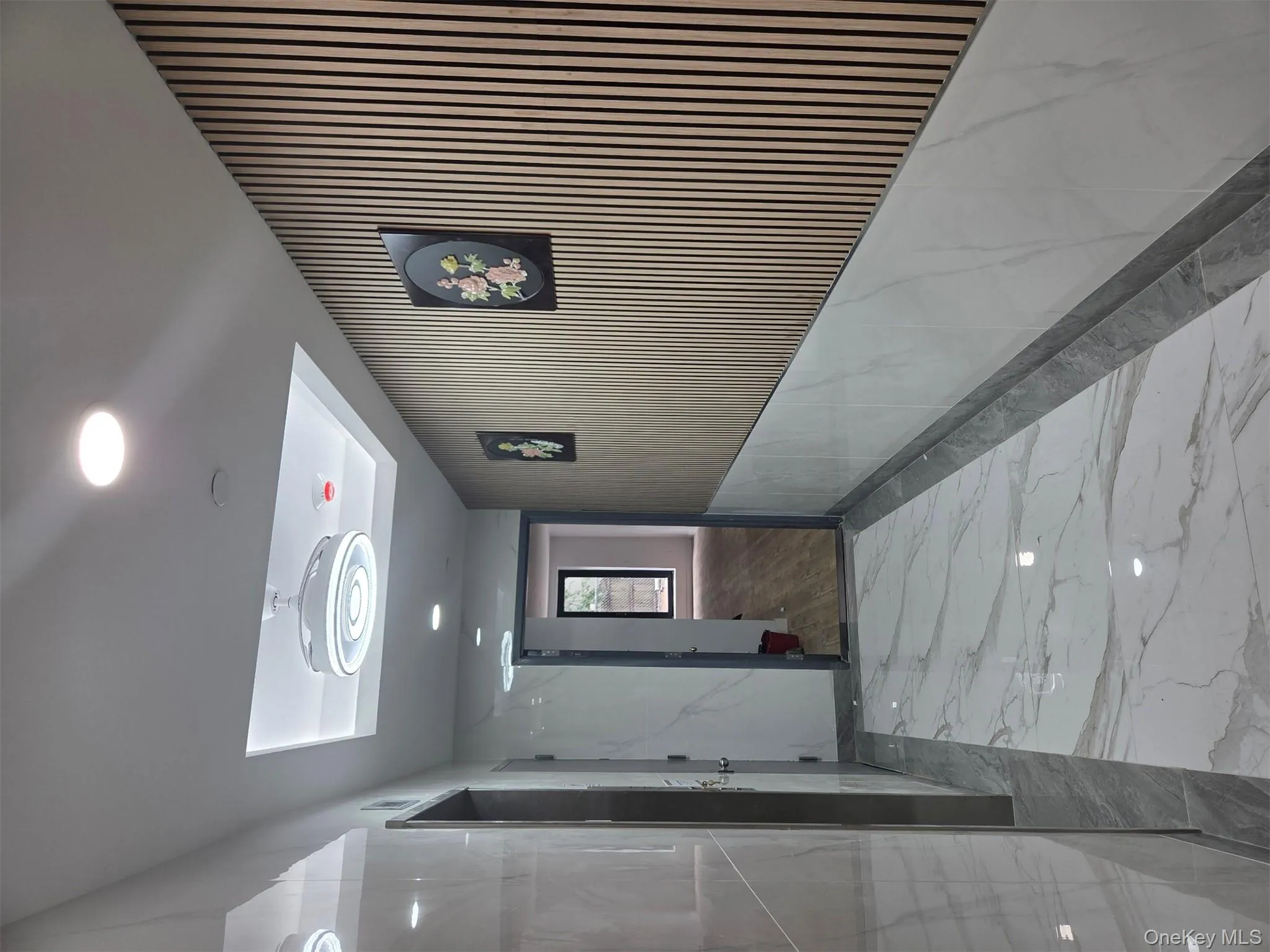 Hallway featuring marble tiled floors, a raised ceiling, and recessed lighting Hallway featuring marble tiled floors, a raised ceiling, and recessed lighting
