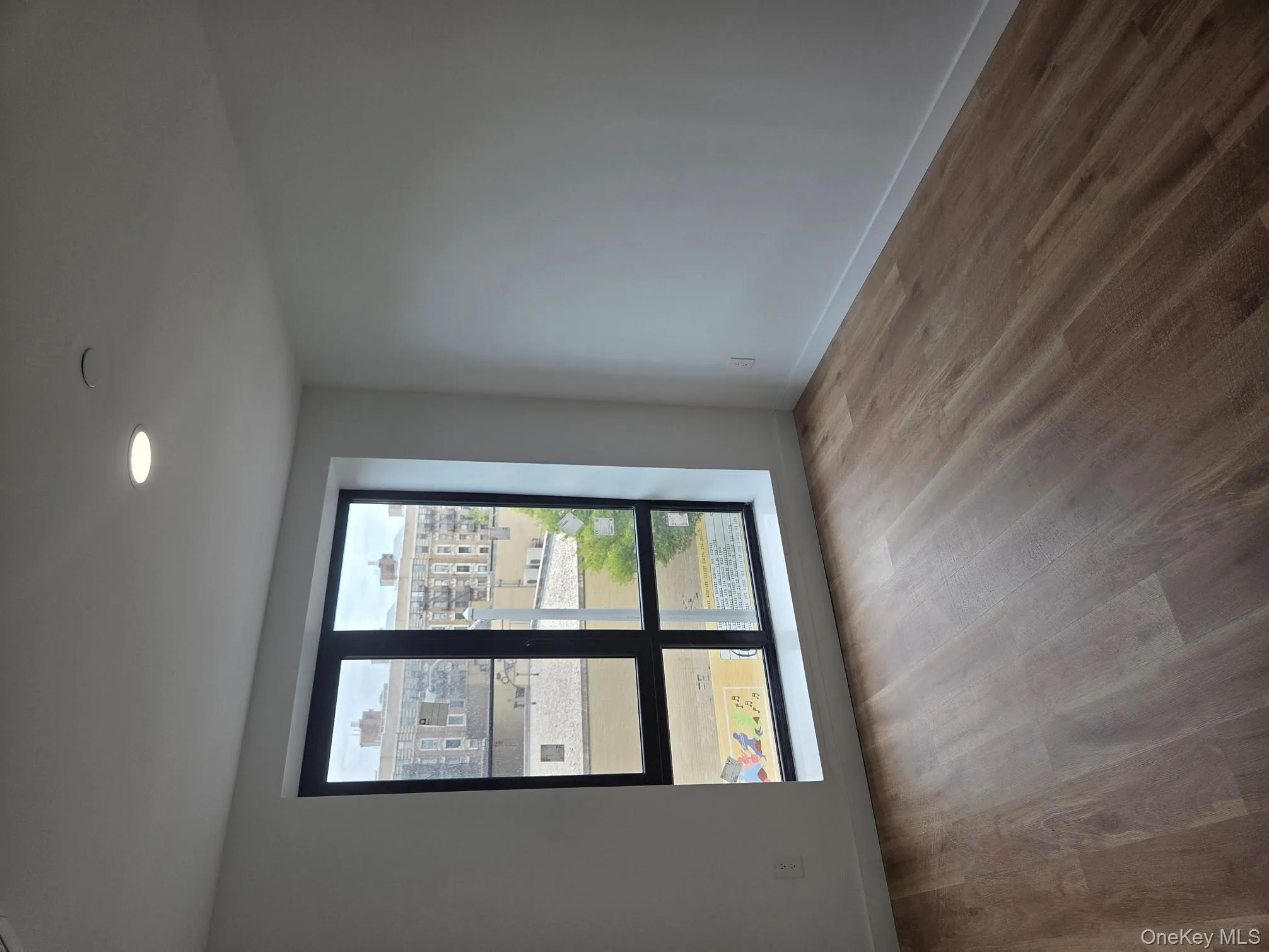 Unfurnished room featuring light wood-style flooring, recessed lighting, and a view of city Unfurnished room featuring light wood-style flooring, recessed lighting, and a view of city