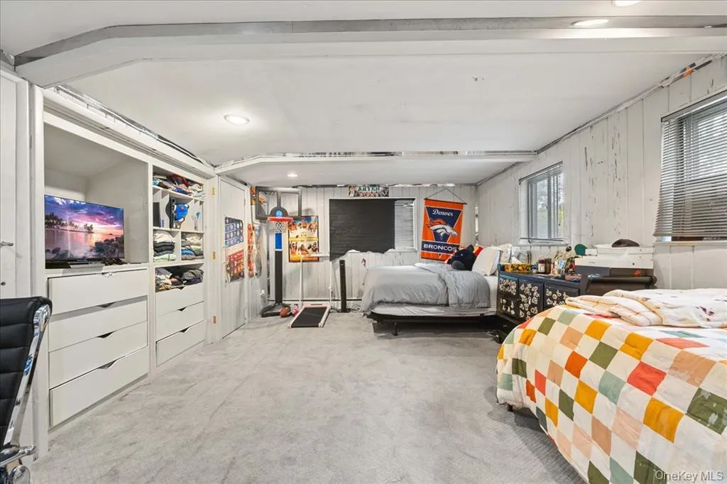 Carpeted bedroom with wood walls and recessed lighting Carpeted bedroom with wood walls and recessed lighting