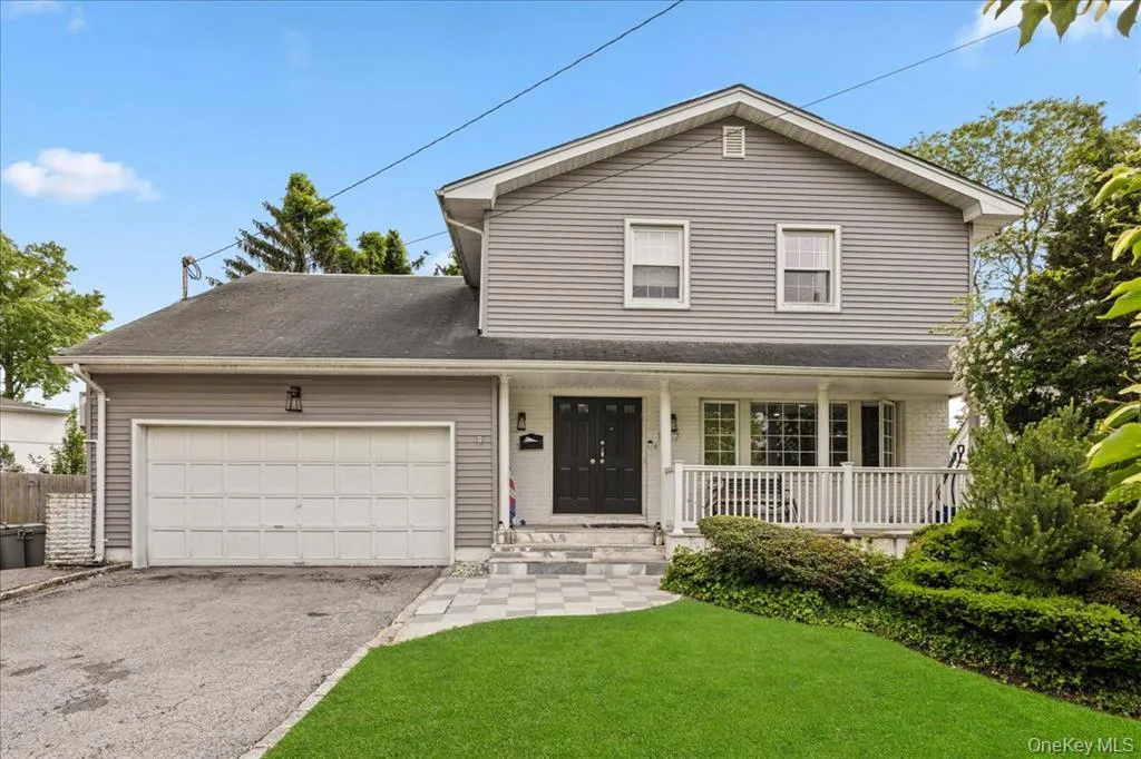 Traditional-style home featuring covered porch, an attached garage, a front yard, and driveway Traditional-style home featuring covered porch, an attached garage, a front yard, and driveway