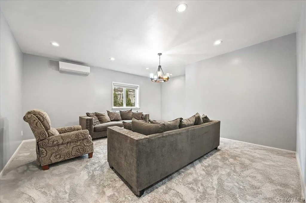 Living area featuring carpet, recessed lighting, a chandelier, and a wall mounted air conditioner Living area featuring carpet, recessed lighting, a chandelier, and a wall mounted air conditioner