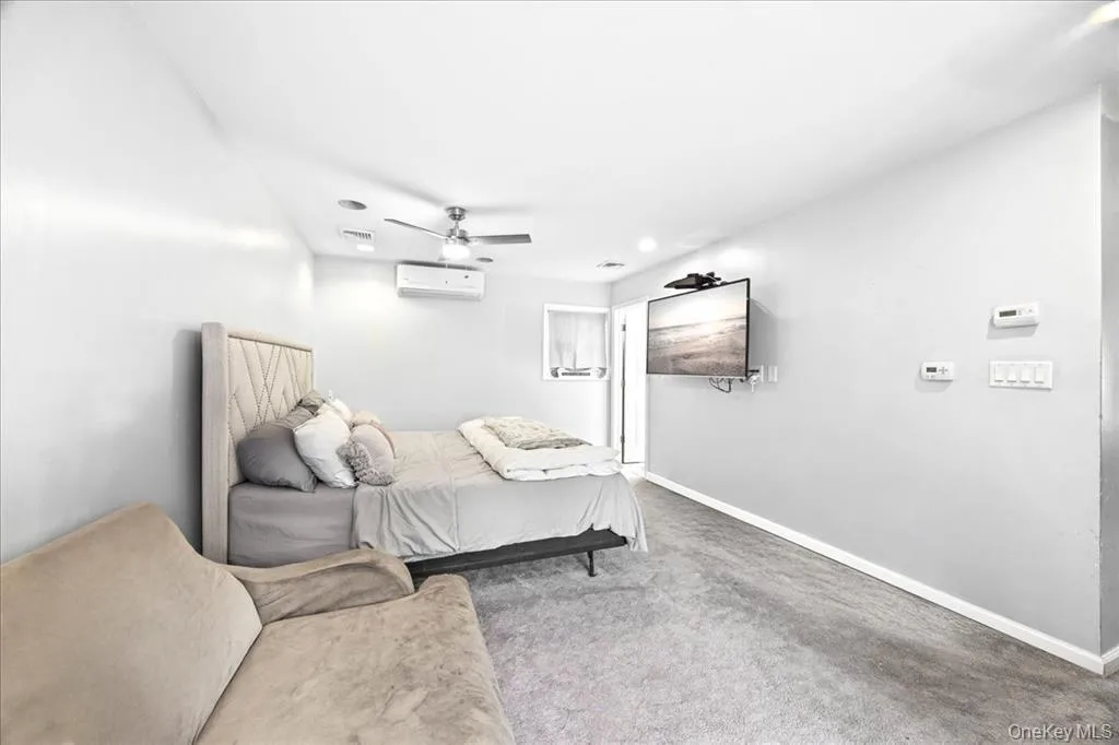 Carpeted bedroom with ceiling fan and a wall mounted air conditioner Carpeted bedroom with ceiling fan and a wall mounted air conditioner